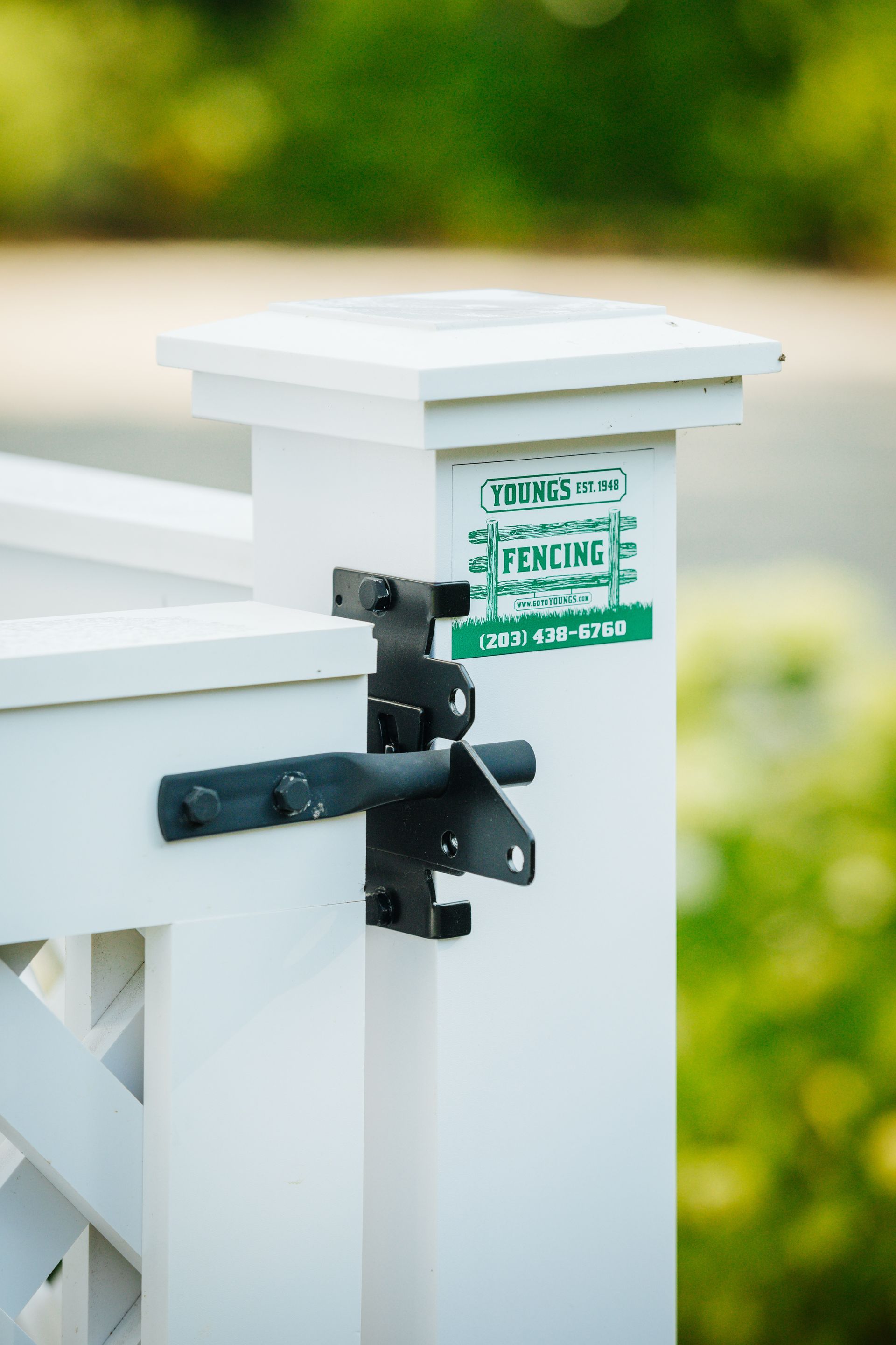 A white fence post with a green sticker on it