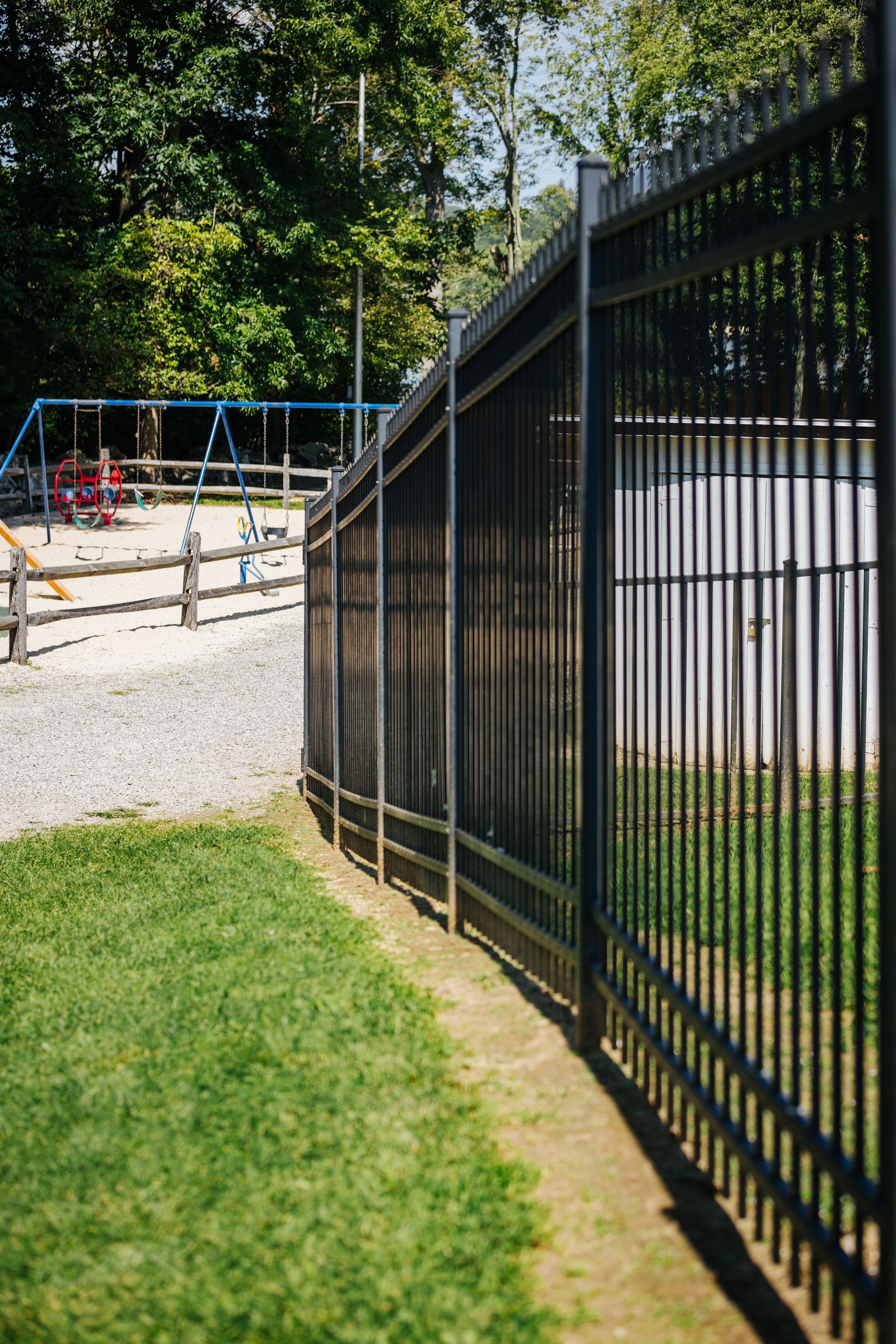 A black metal fence surrounds a playground in a park.