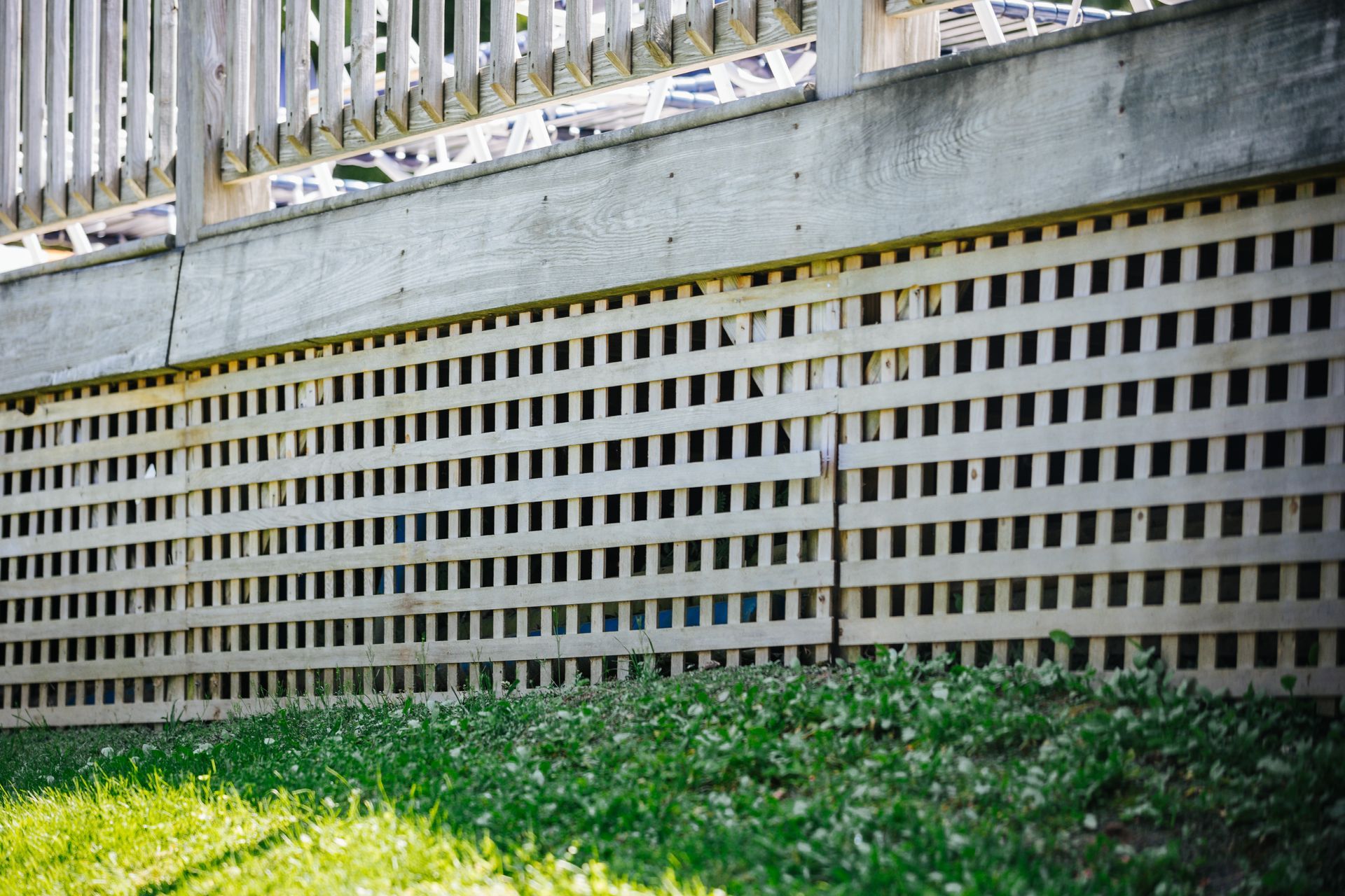 A wooden fence with holes in it is surrounded by grass.