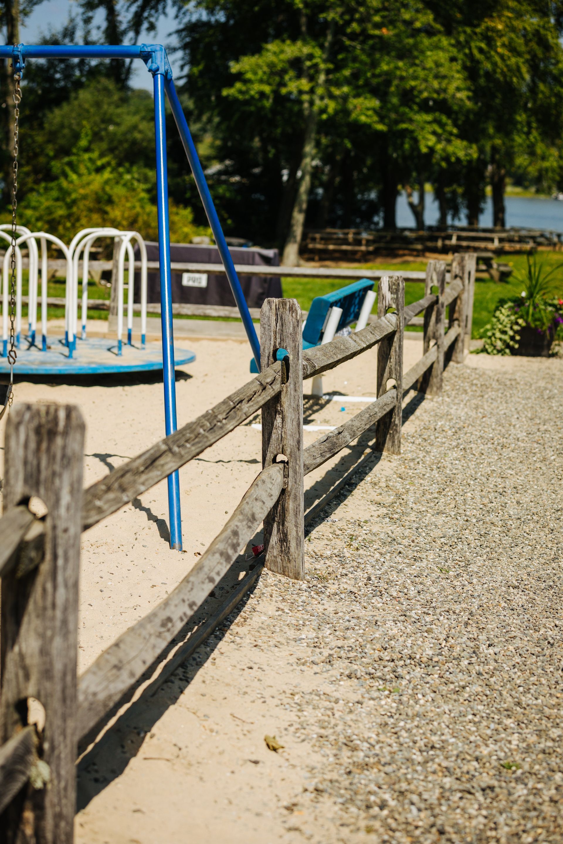 A wooden fence surrounds a playground in a park.