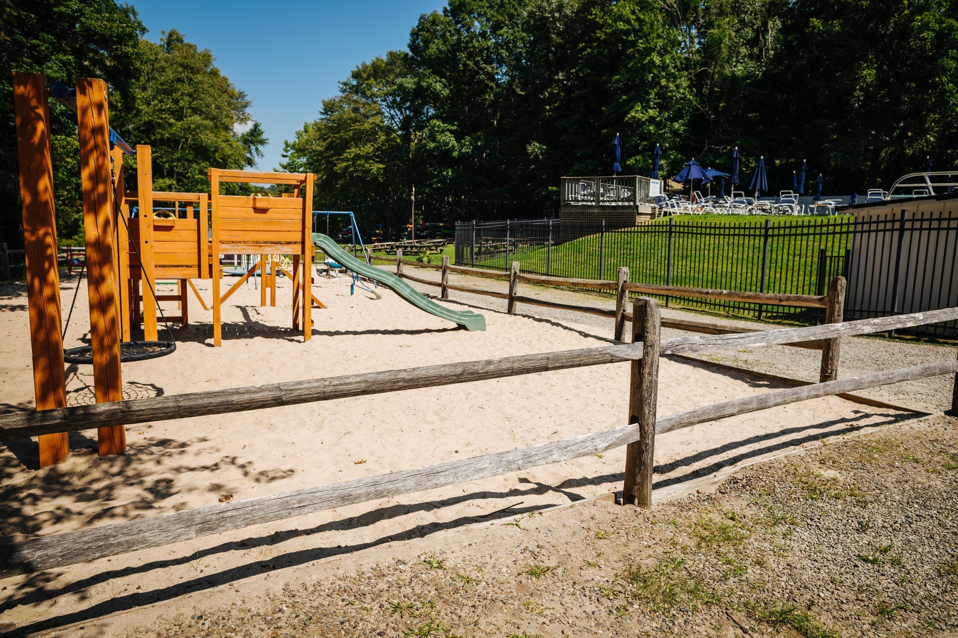 A wooden fence surrounds a playground in a park.