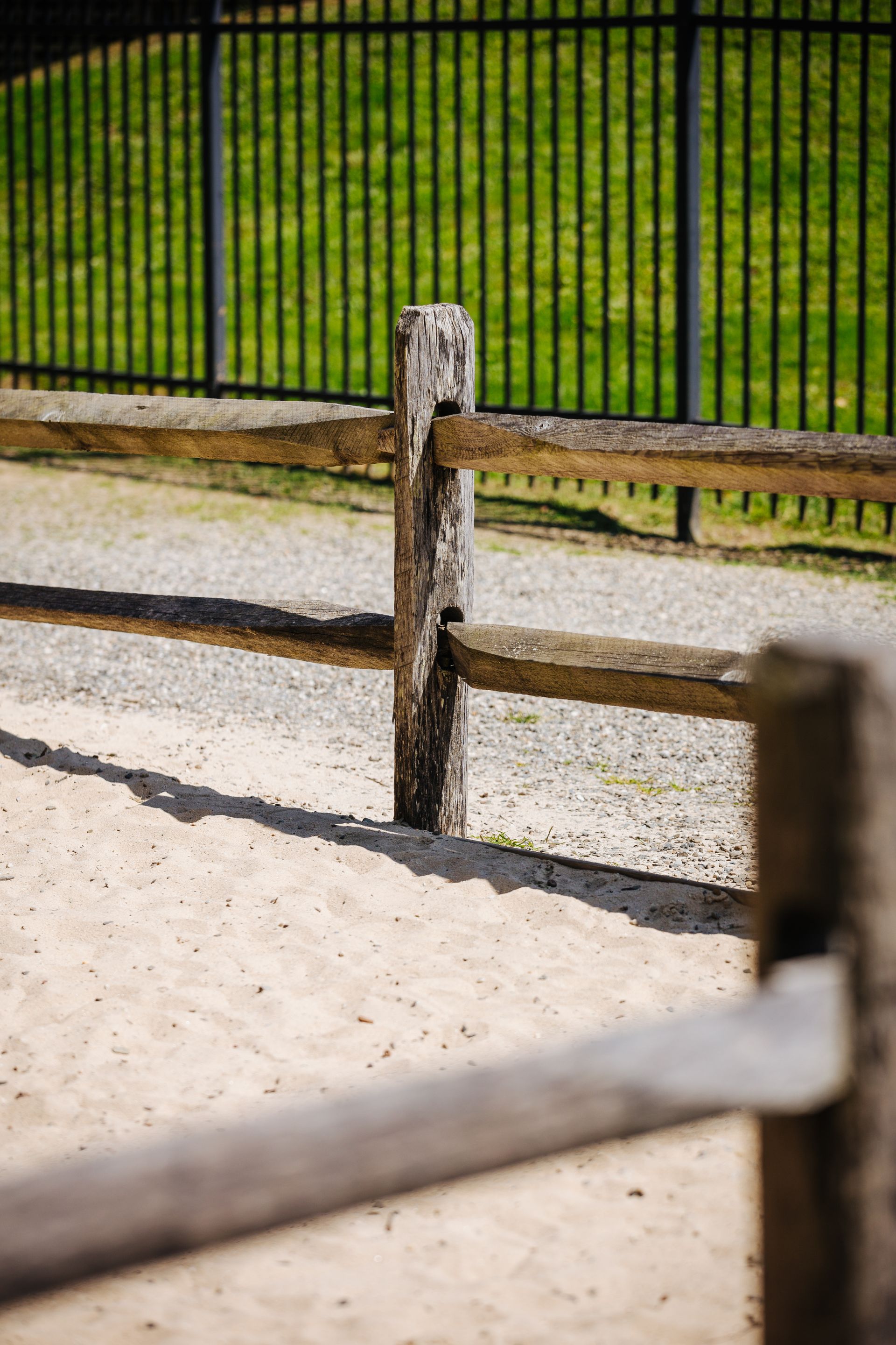 A wooden fence with a metal fence in the background.