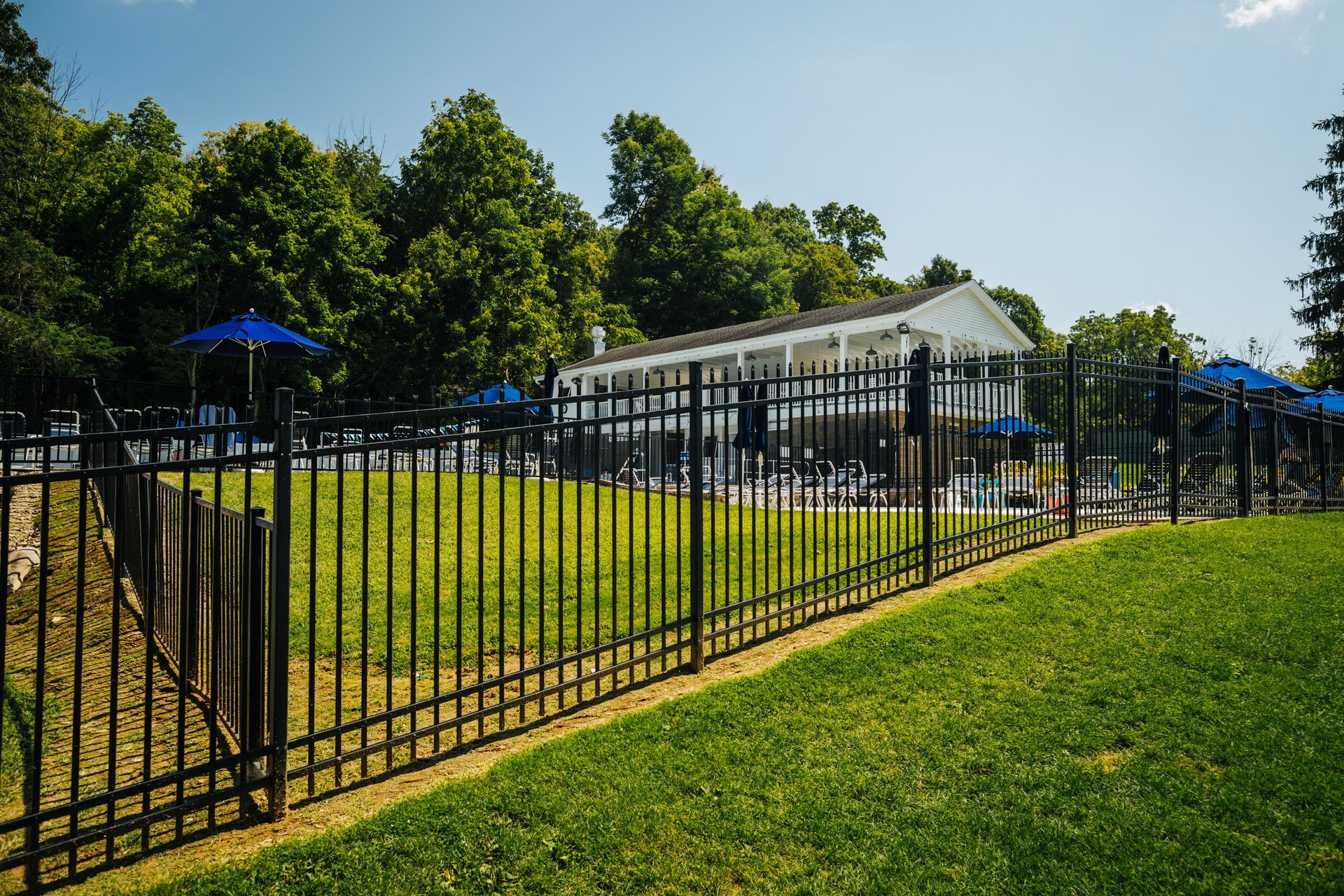 A black metal fence surrounds a lush green field.