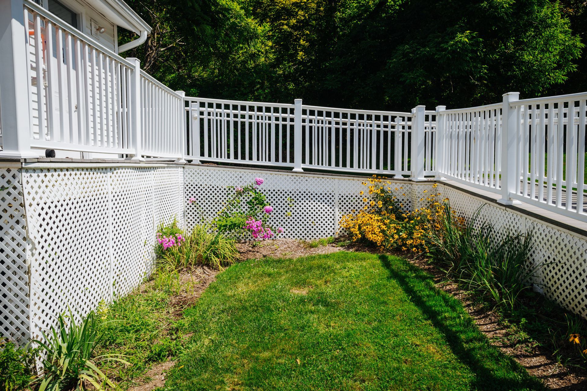 A backyard with a white fence and a lush green lawn