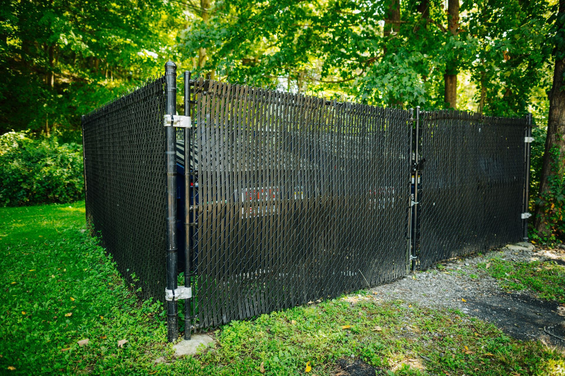 A black chain link fence is surrounded by trees and grass.