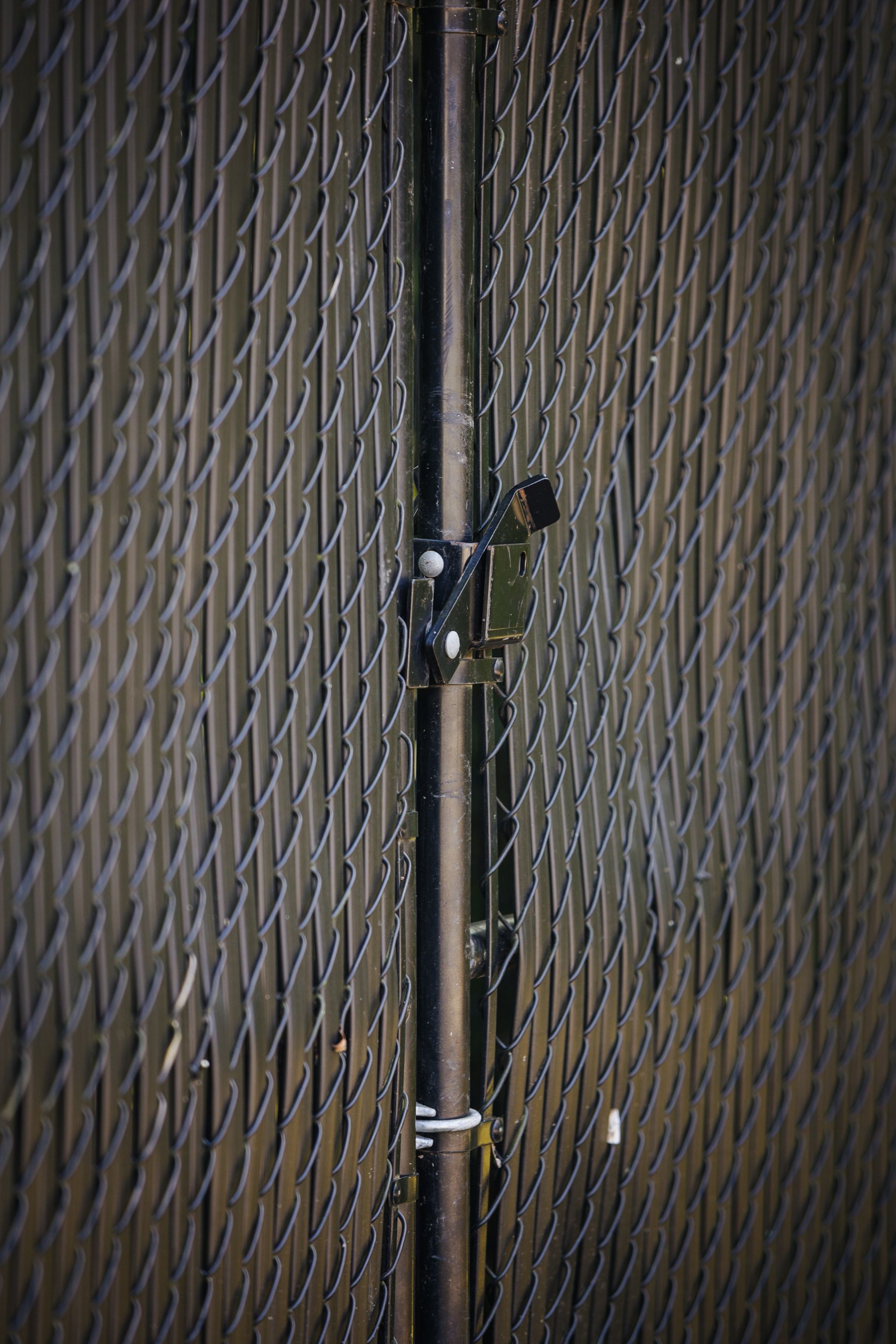 A close up of a chain link fence with a pipe attached to it.