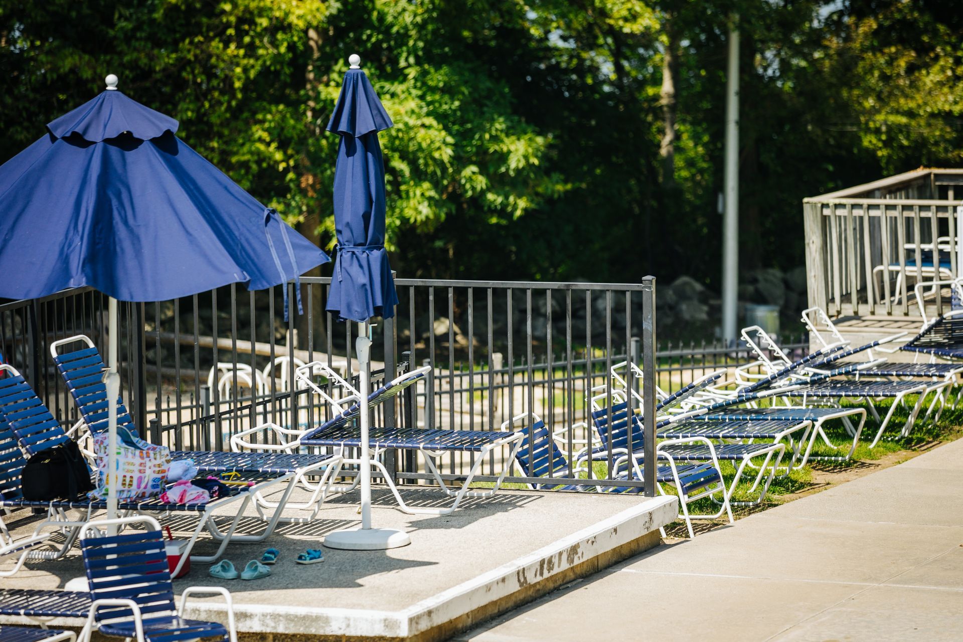 A row of chairs and umbrellas are lined up in front of a pool.