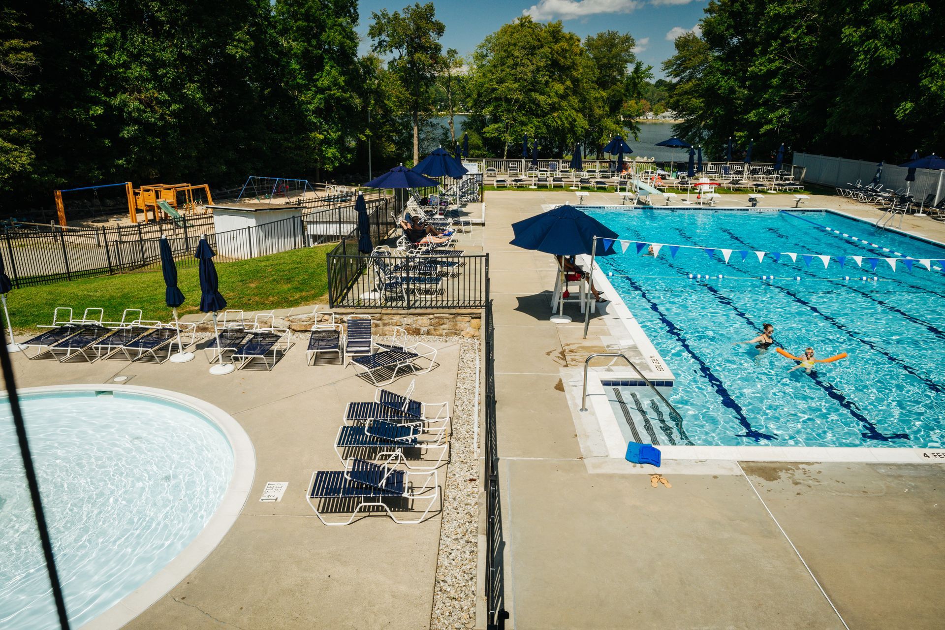 A large swimming pool surrounded by chairs and umbrellas