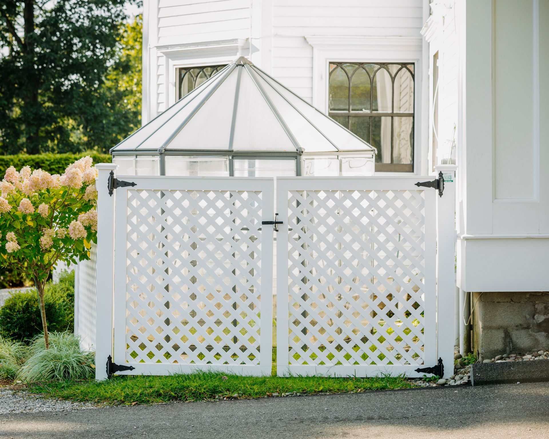A white fence is in front of a white house.