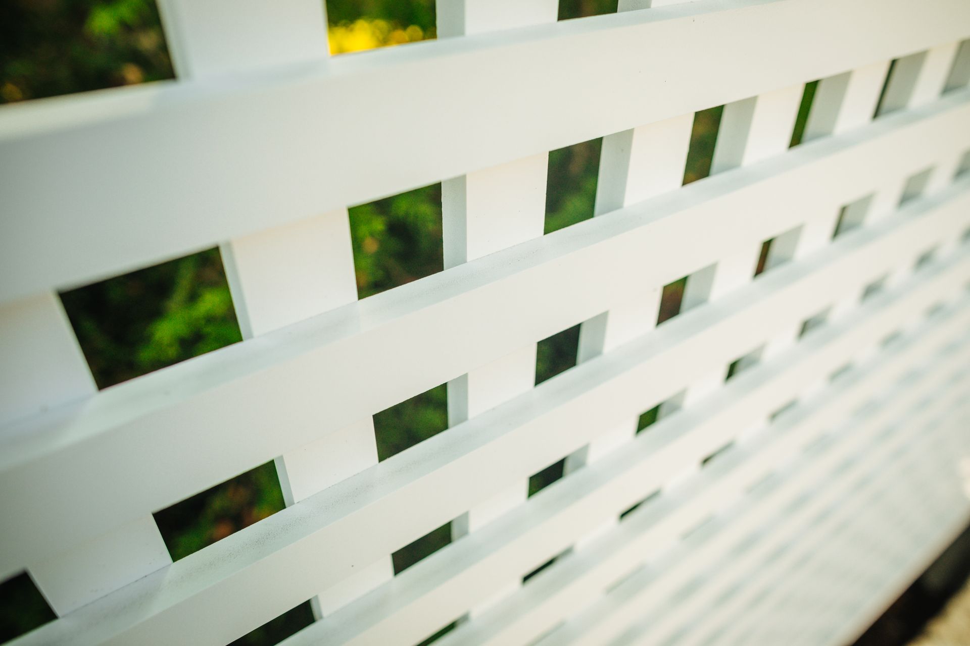 A close up of a white lattice fence with squares cut out of it