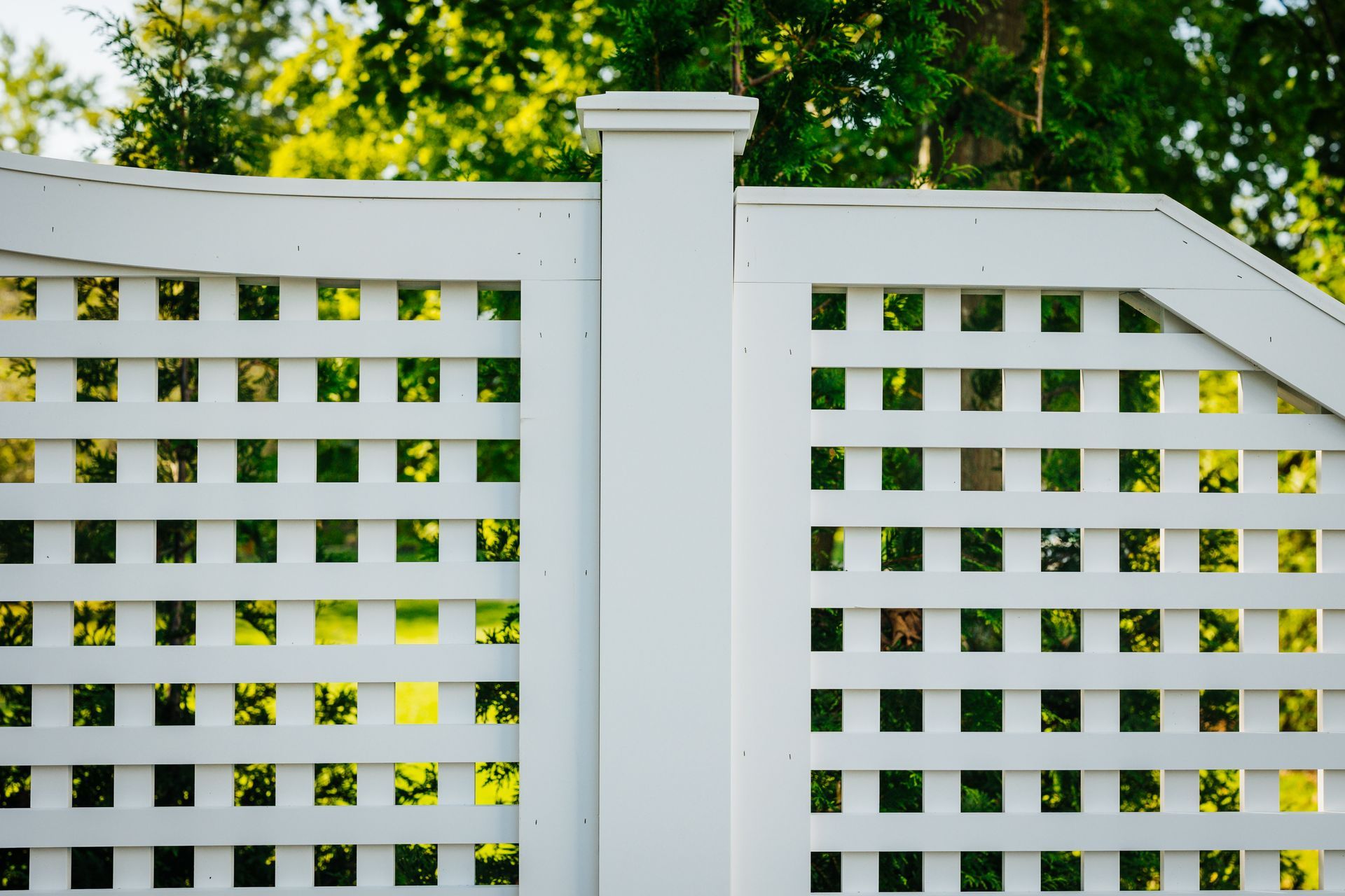A white lattice fence with trees in the background