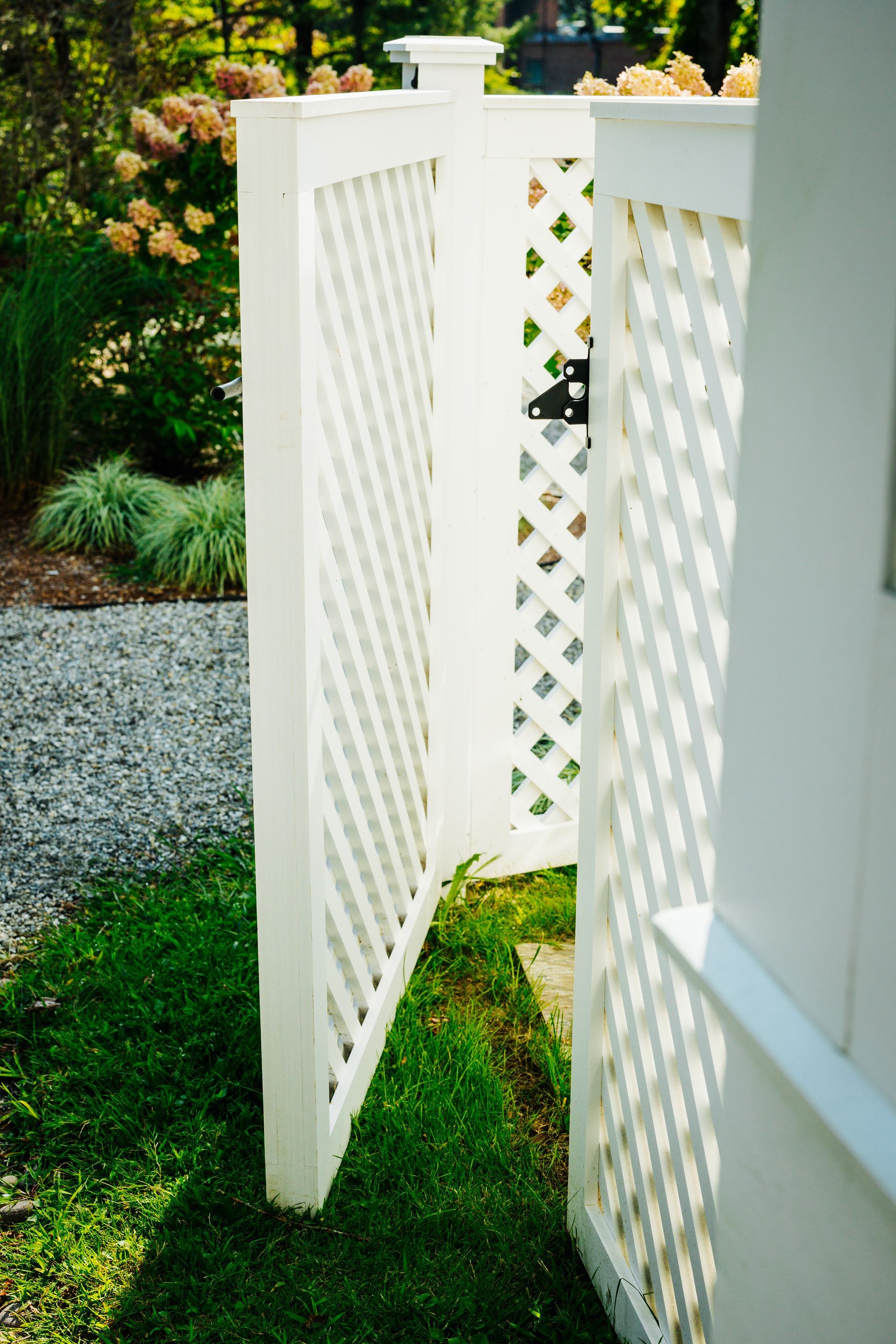 A white fence with a lattice design is sitting in the grass.