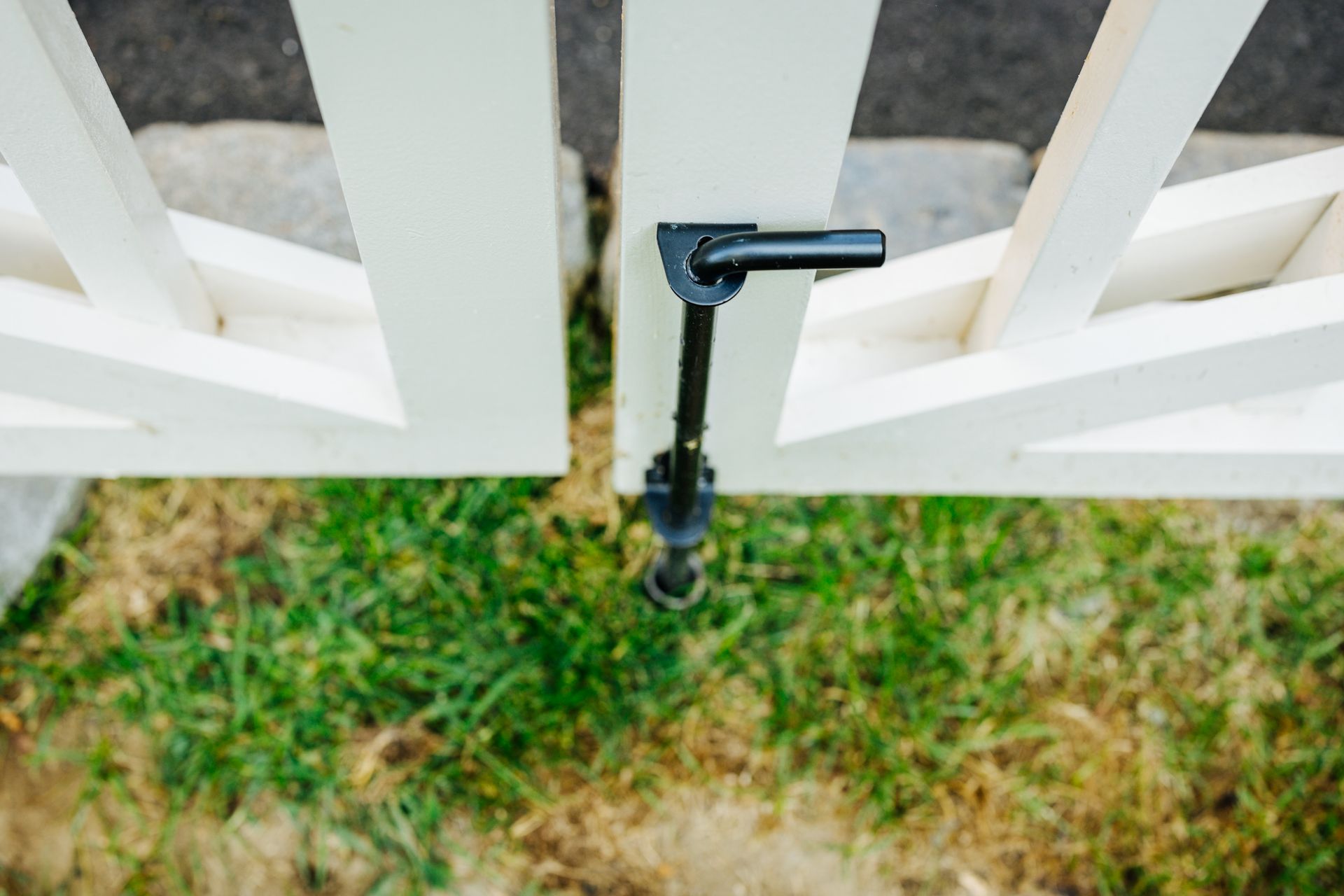 A white fence with a black latch is sitting in the grass.