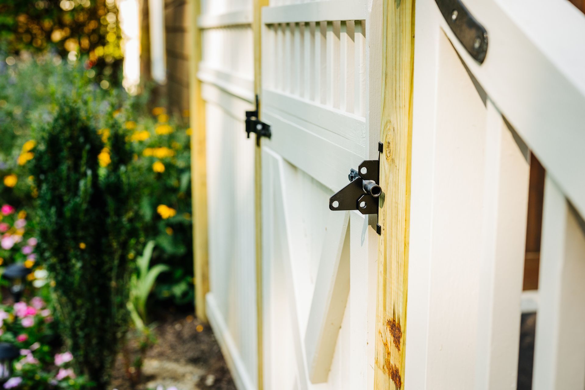 A close up of a white fence with flowers in the background.