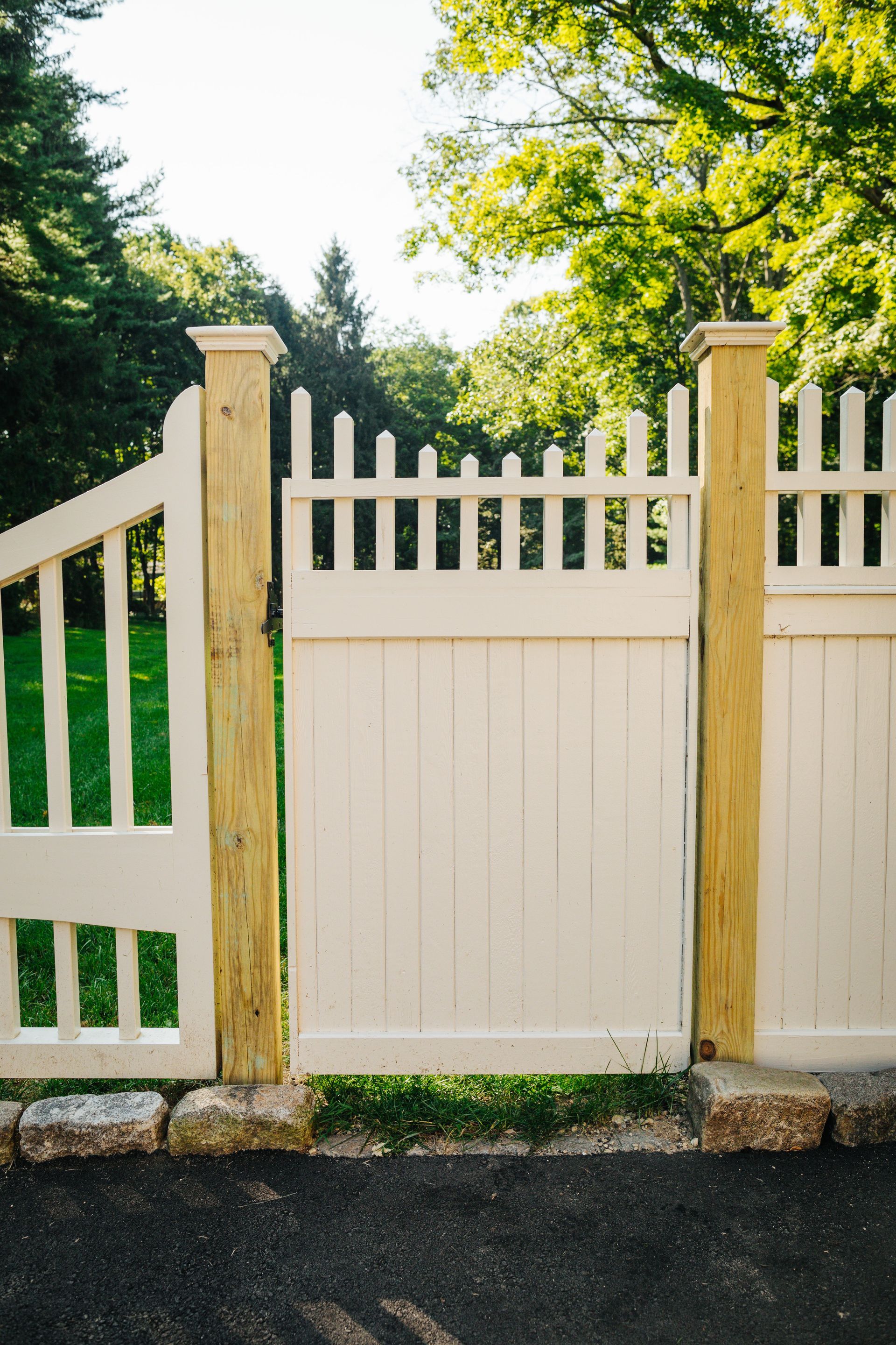 A white fence with a wooden gate leading to a lush green field.