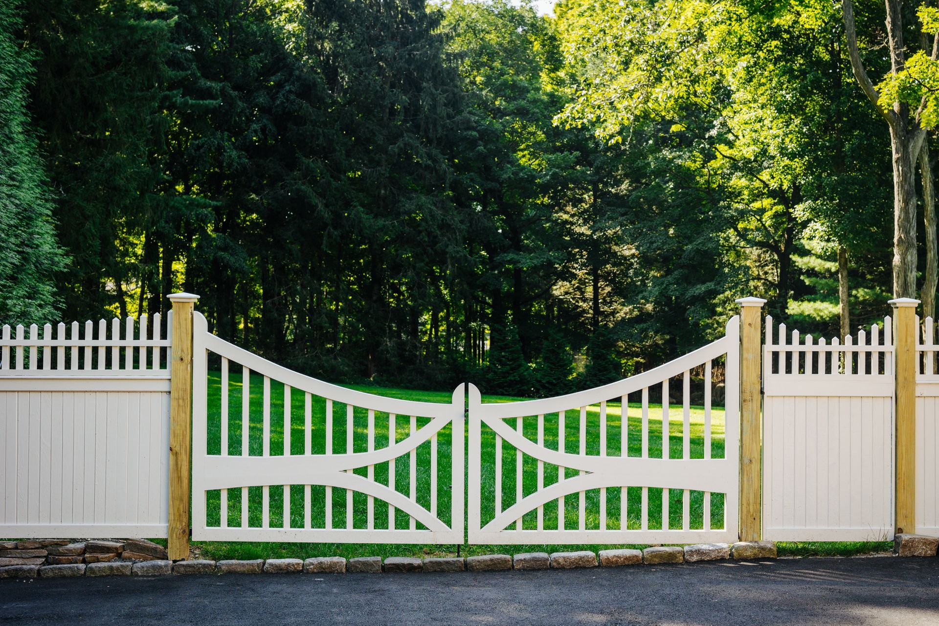 A white fence with a wooden post is surrounded by trees