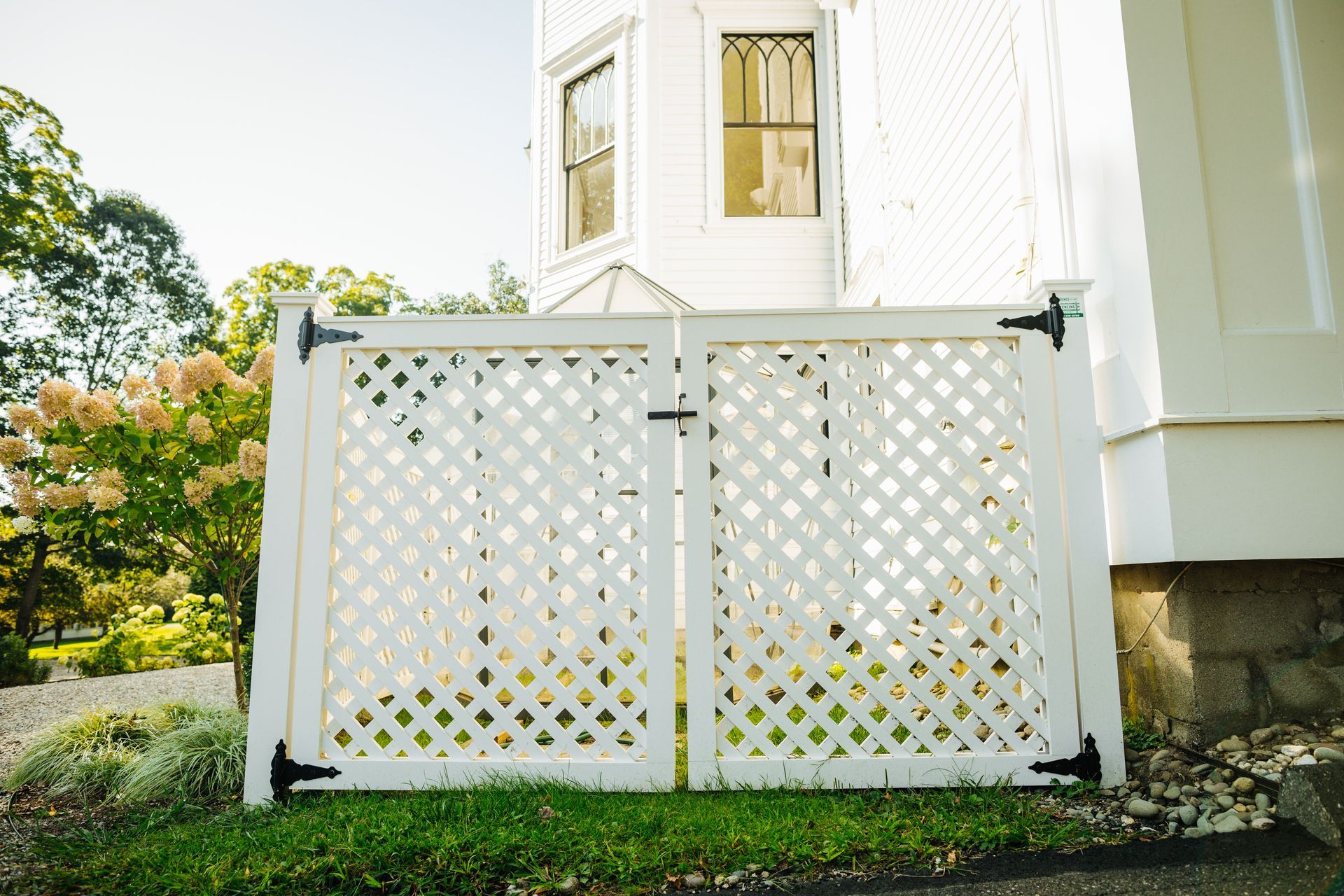 A white lattice fence is in front of a white house.