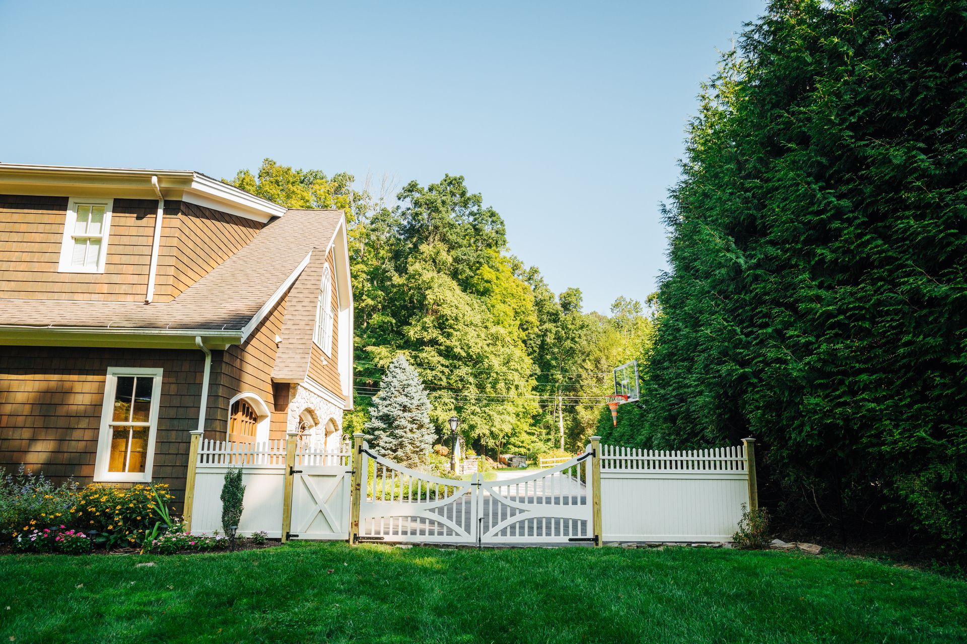 A brown house with a white fence and a gate in front of it.
