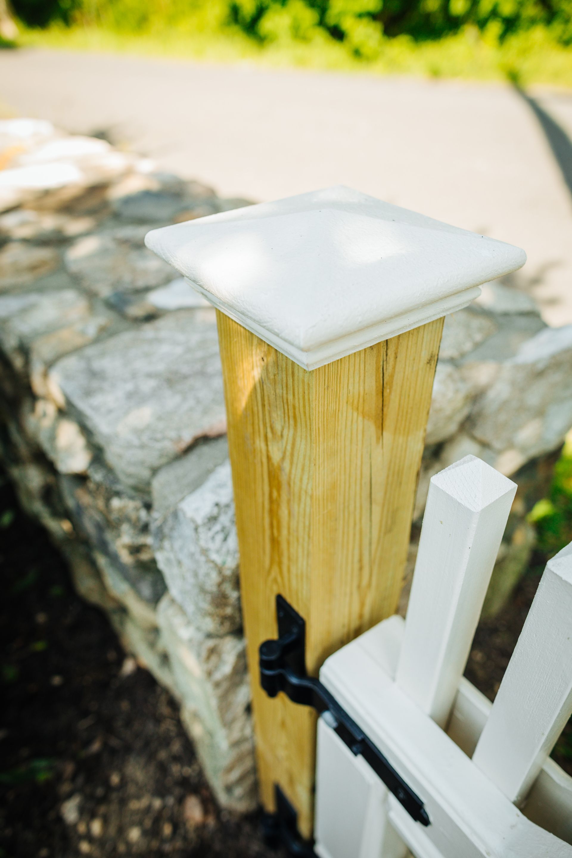 A wooden post with a white top is next to a white fence.