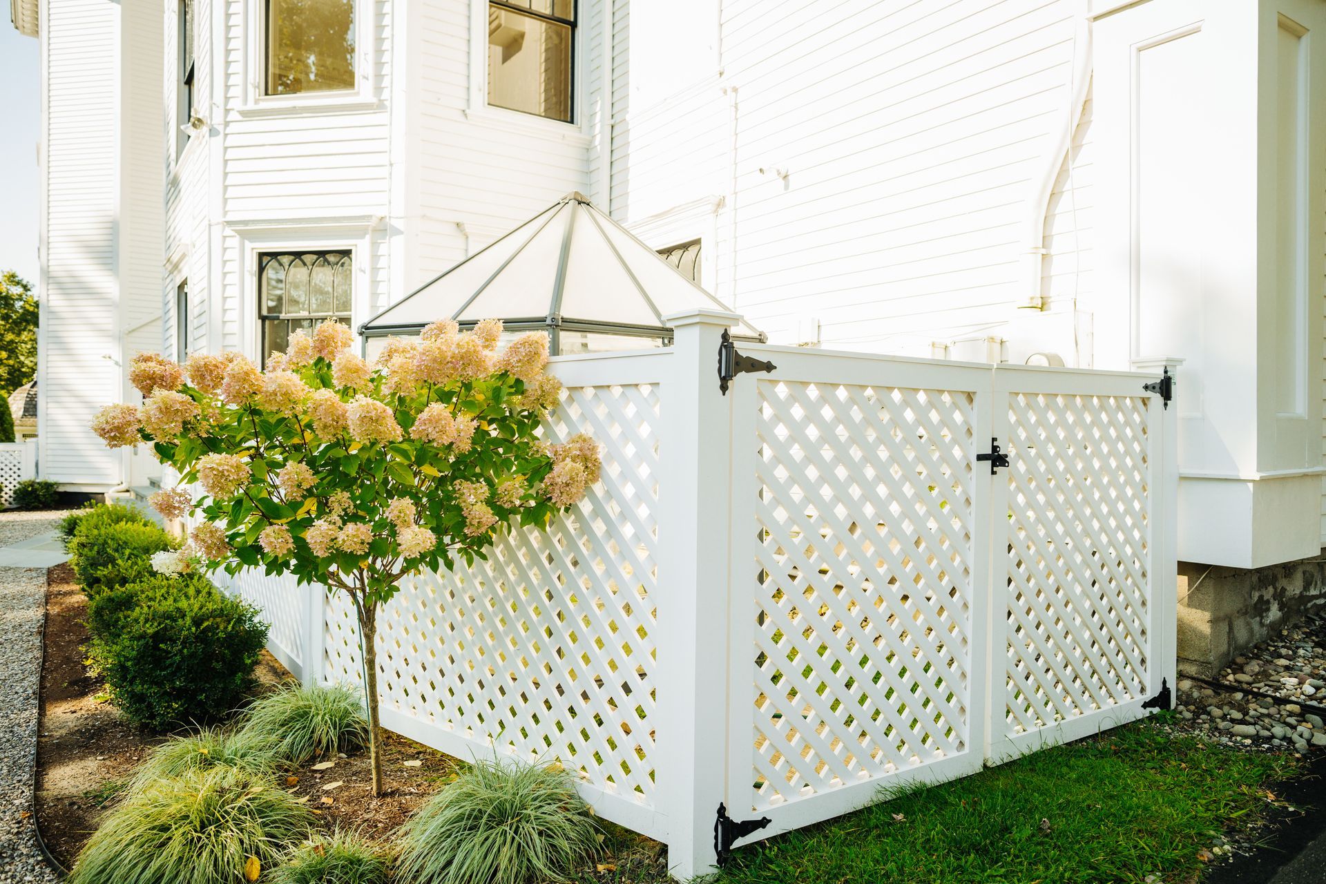 A white lattice fence is in front of a white house.