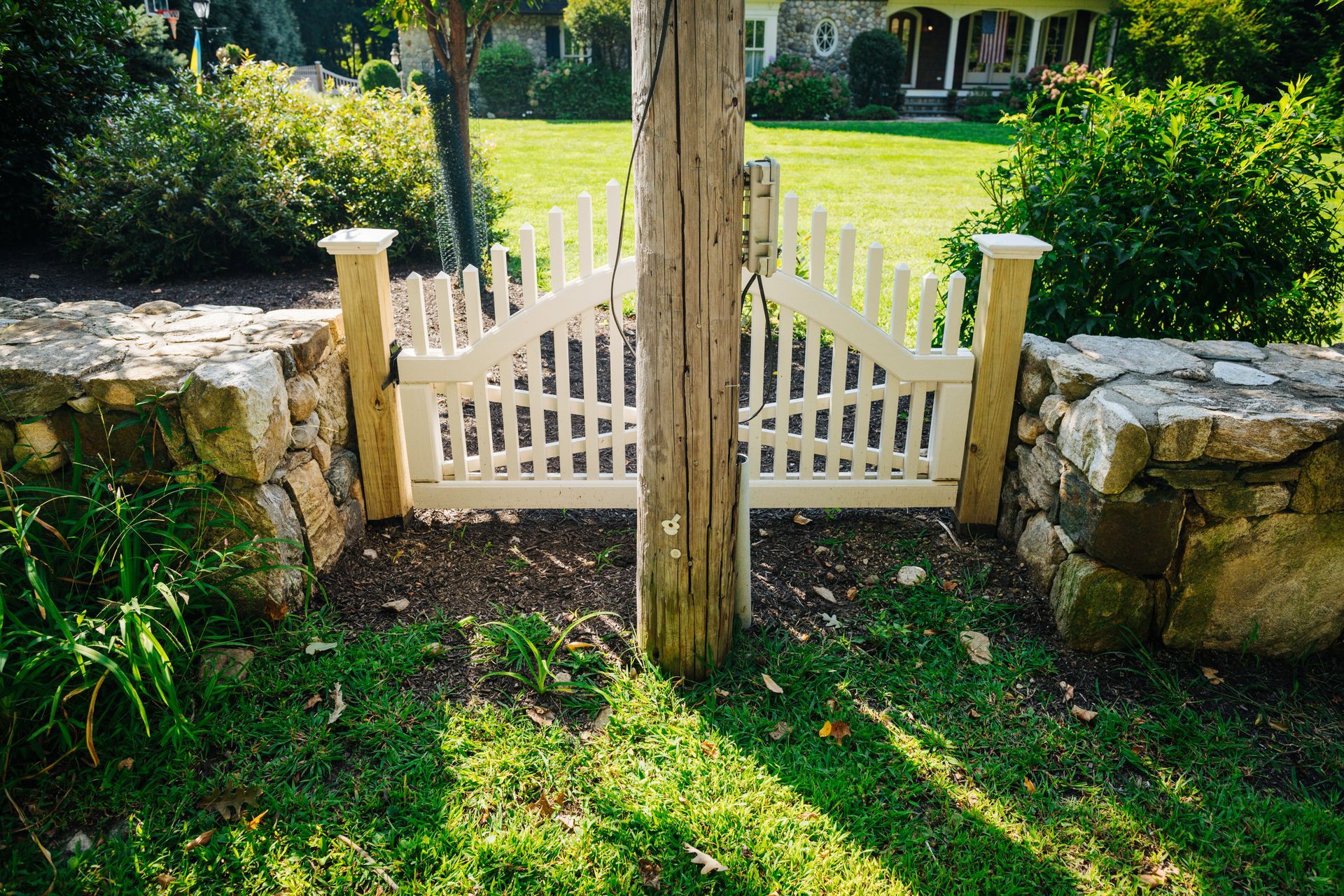 A white gate is sitting in the middle of a lush green field.