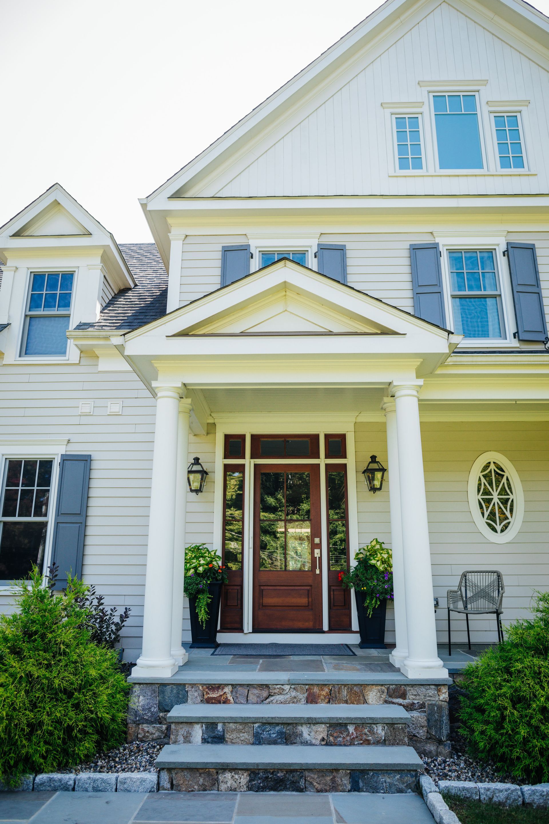A large white house with a porch and stairs leading to the front door.