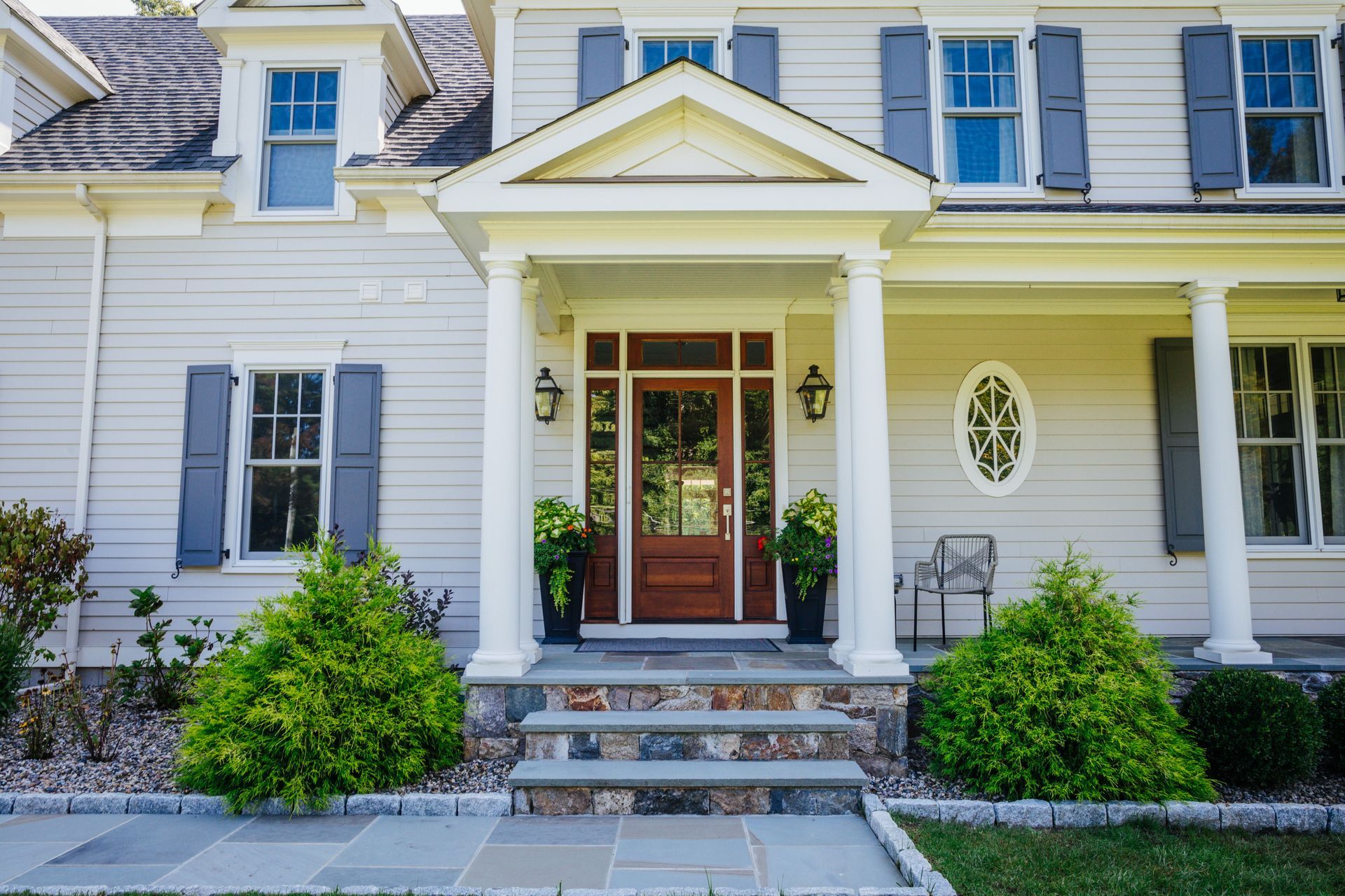 A large white house with a porch and stairs