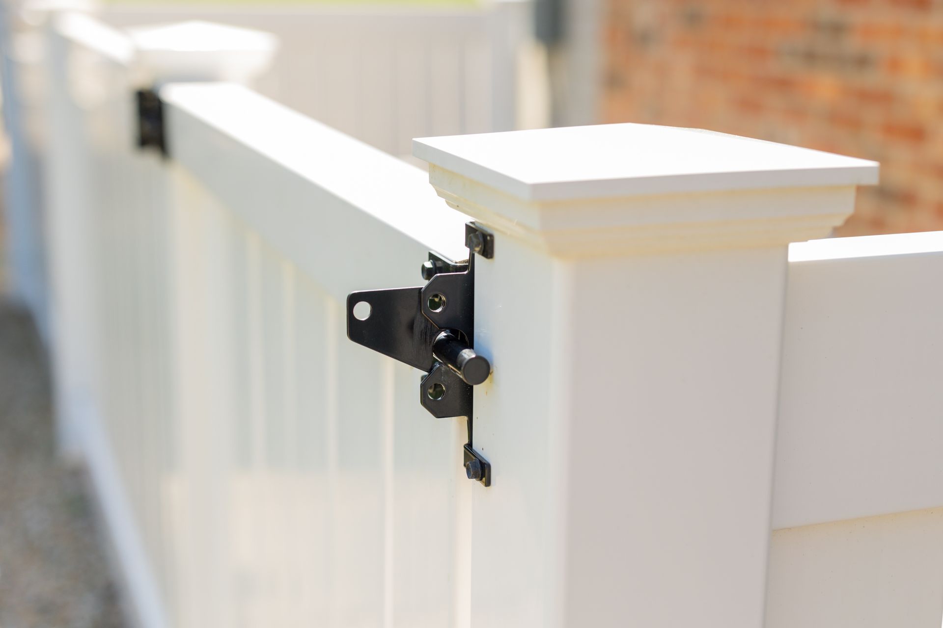 A white fence with a black latch attached to it.