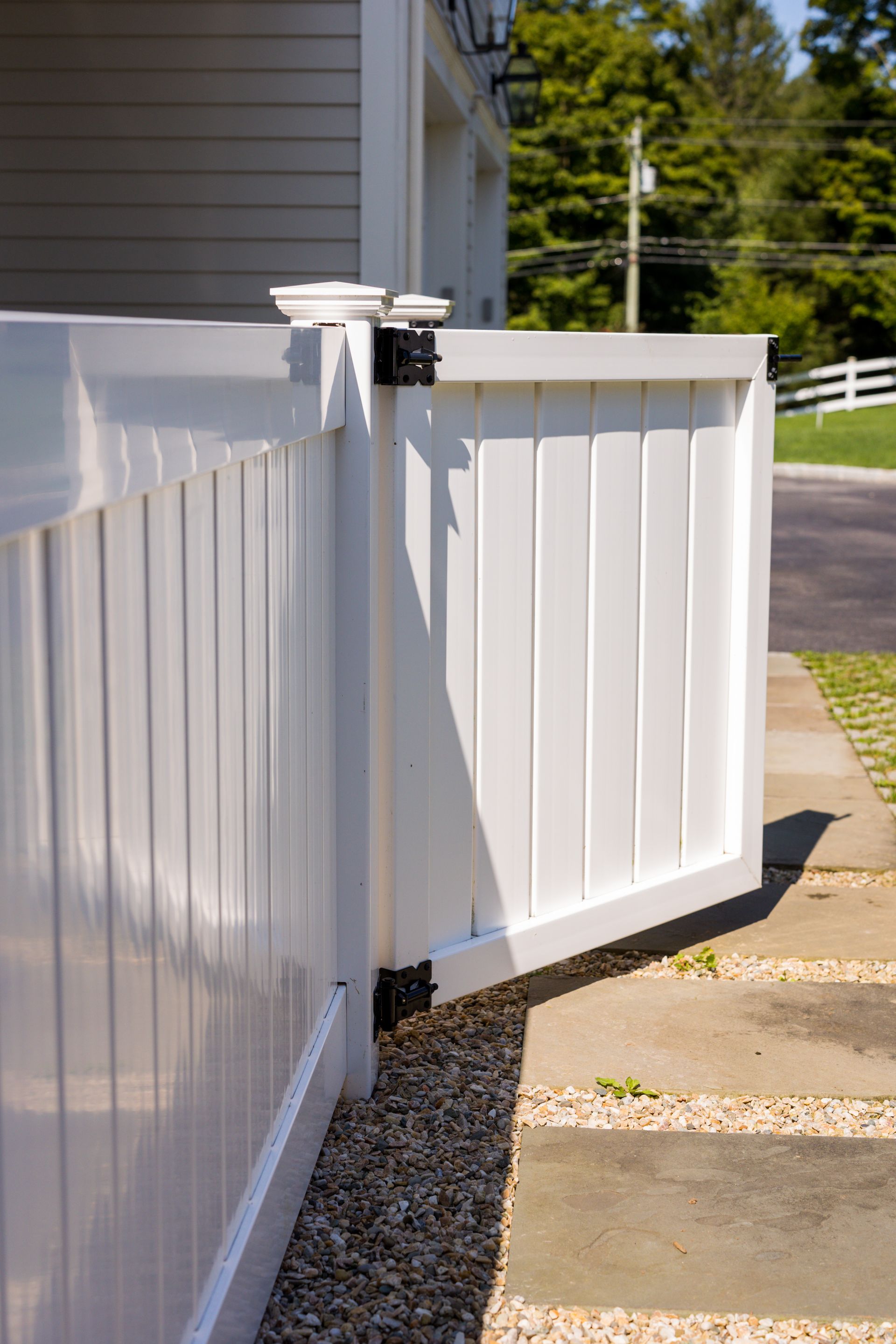 A white fence with a gate open in front of a house.