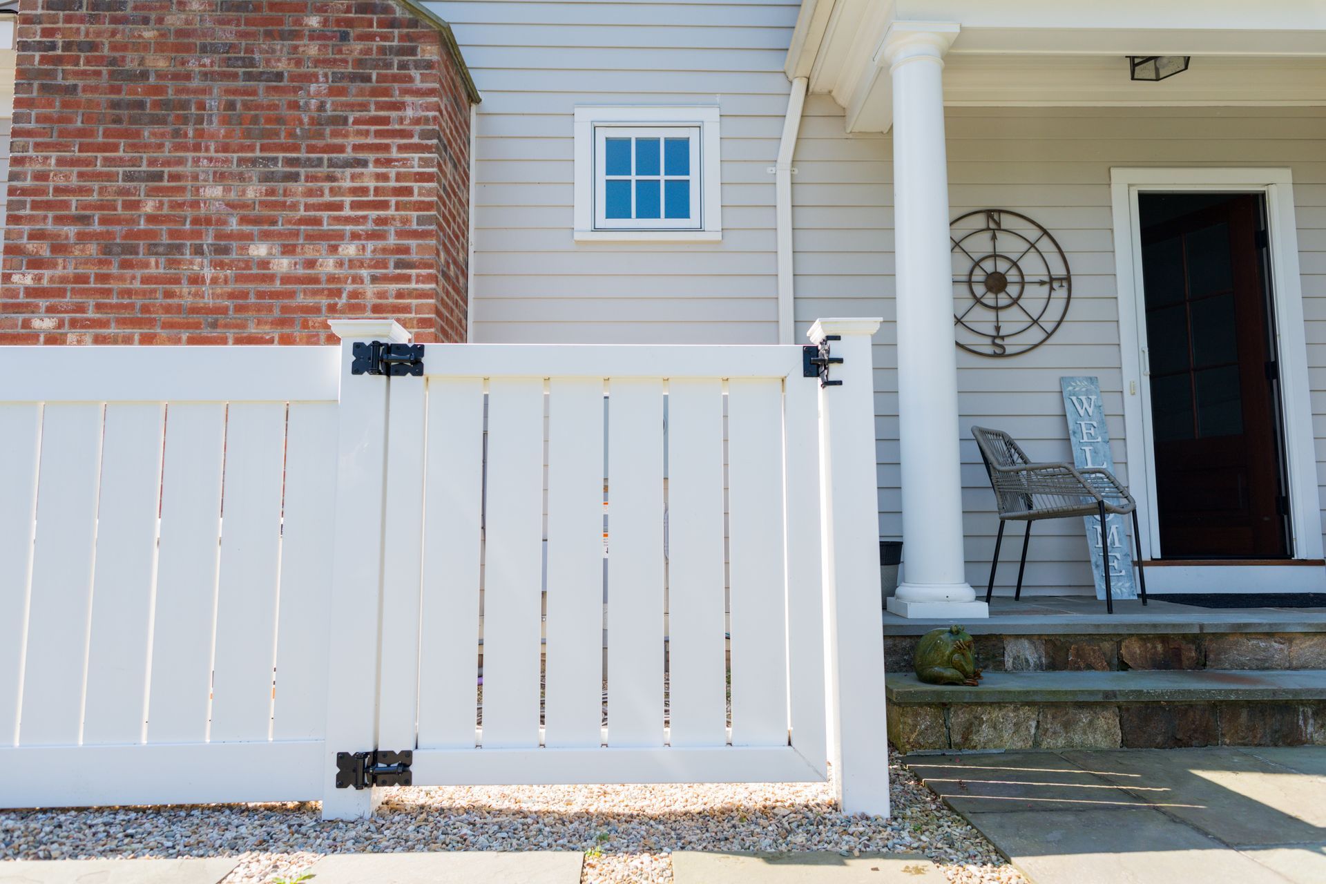 A white fence is in front of a brick house.