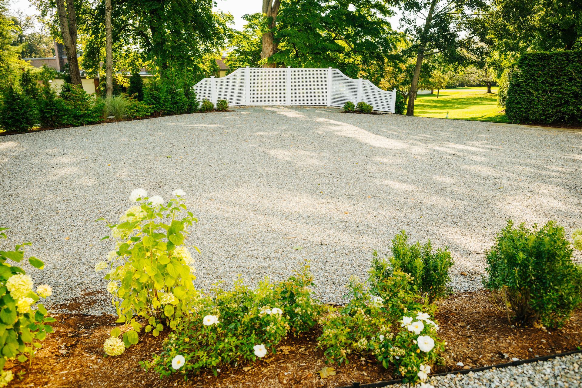 A gravel driveway with a white fence in the background