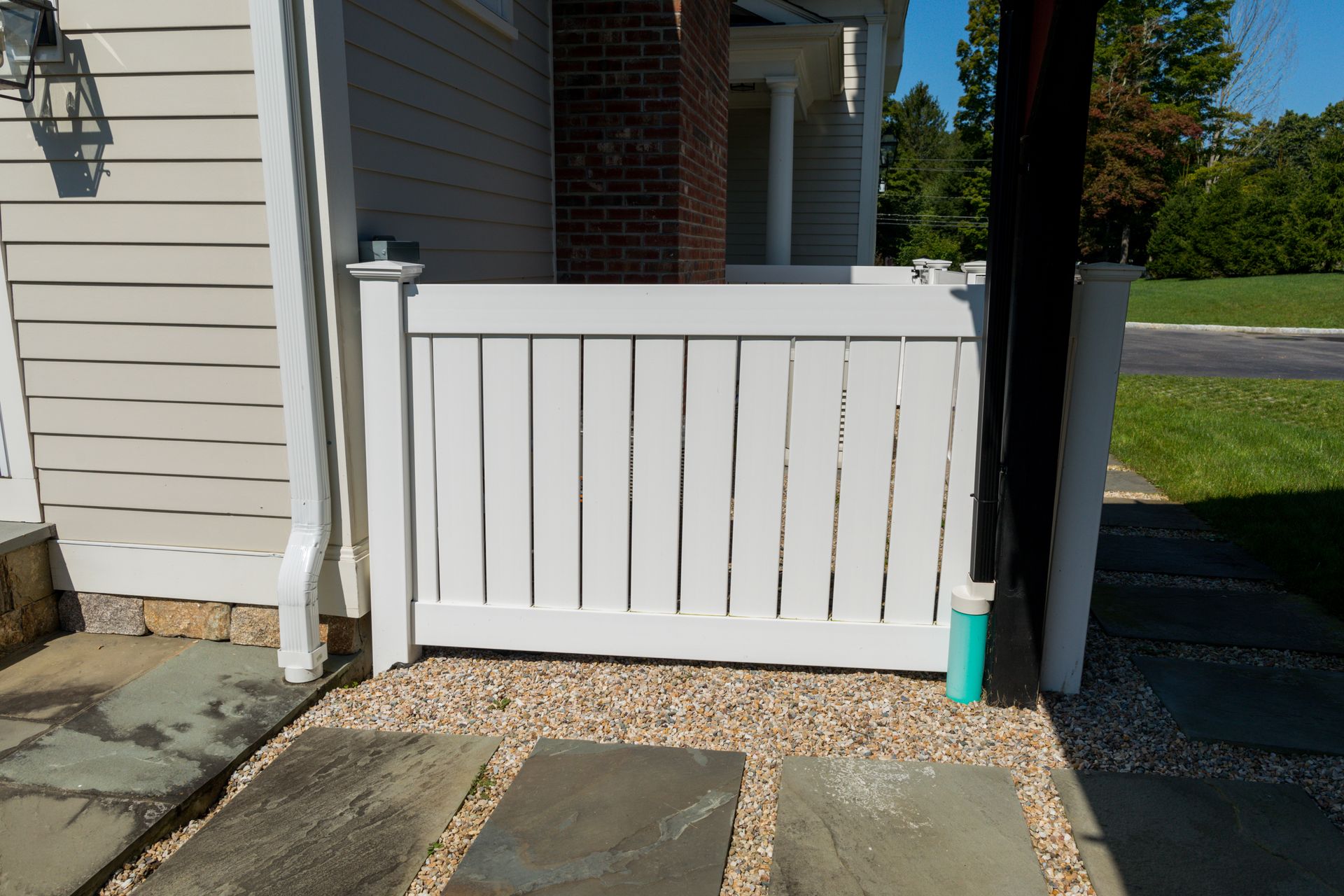 A white fence is sitting in front of a house.