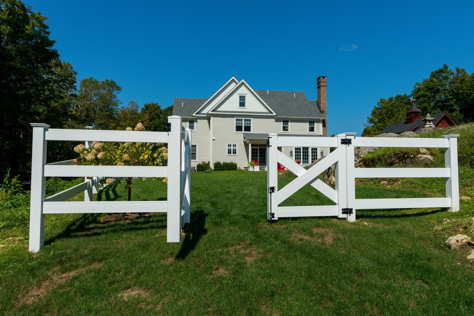 A white fence with a gate in front of a house.