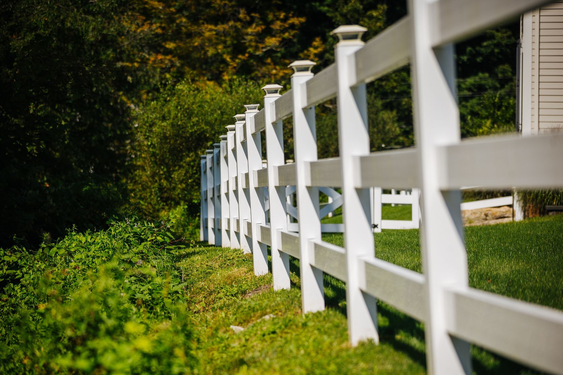 A white fence is surrounded by green grass and trees.