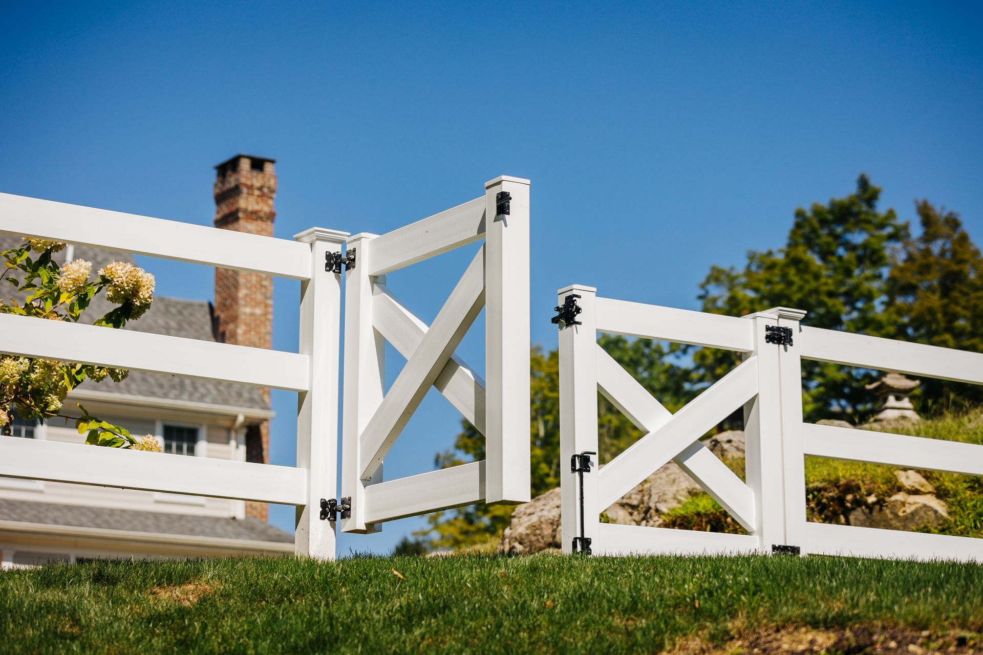 A white fence with a gate in front of a house.