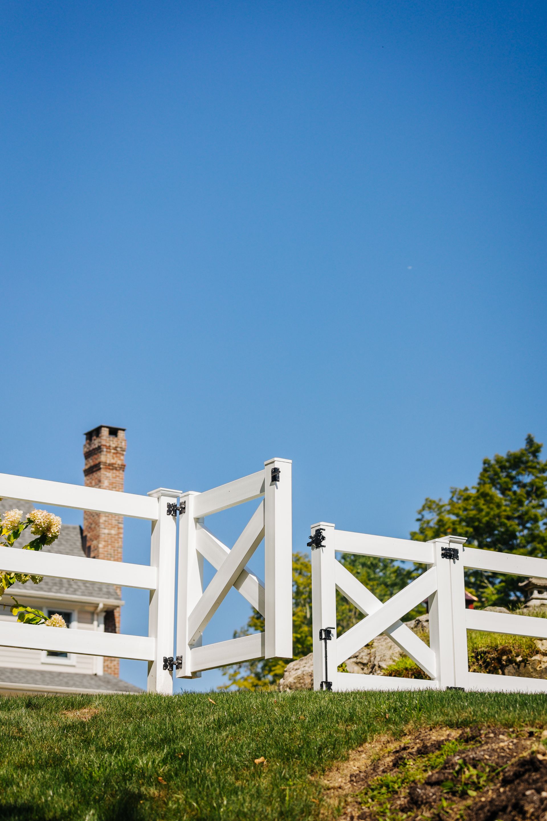 A white fence with a gate is sitting on top of a grassy hill.