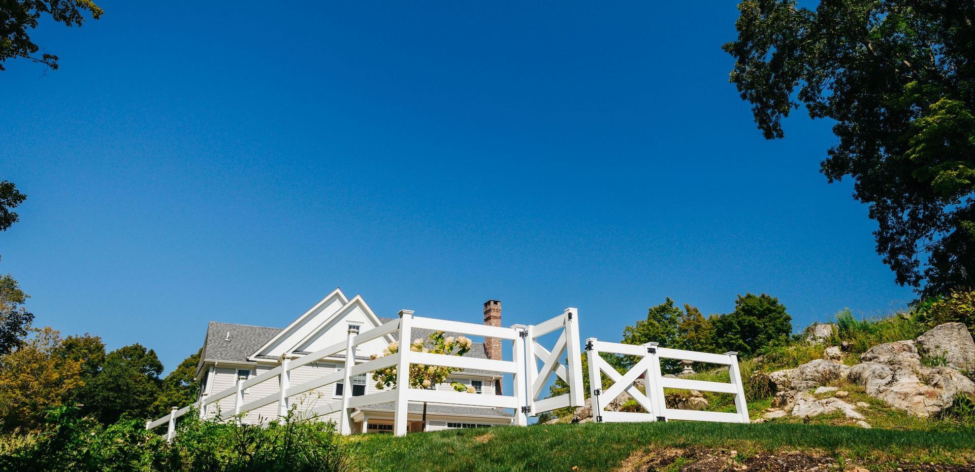 A white fence surrounds a house on a hill.
