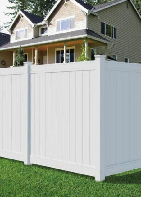 A white fence is in front of a house