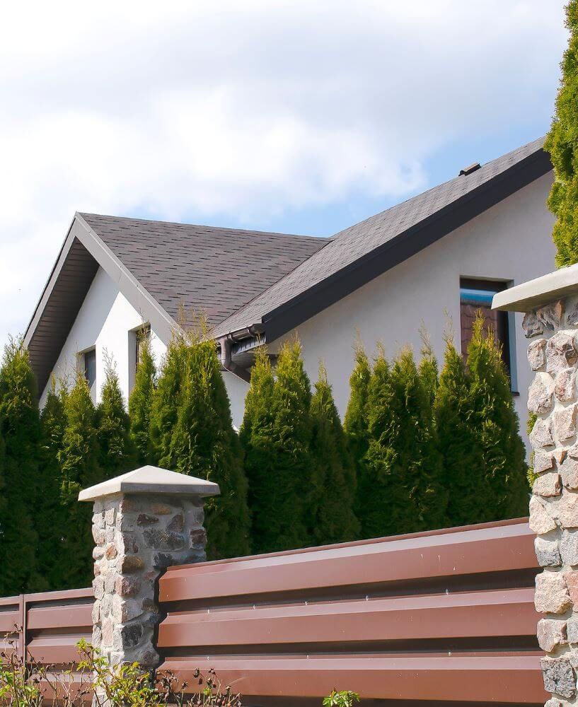 A house with a fence and trees in front of it