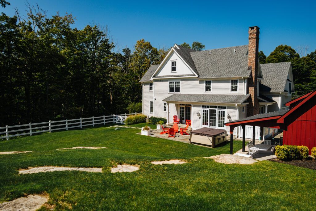 A large white house with a red barn in the backyard.