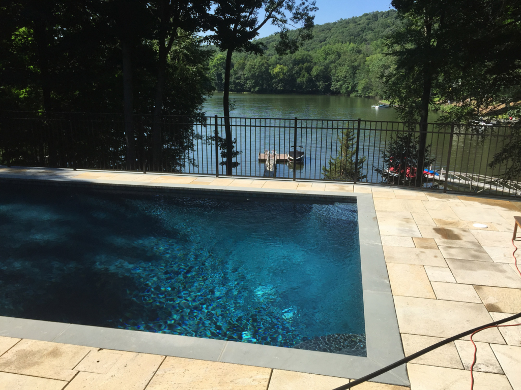 A large swimming pool with a lake in the background