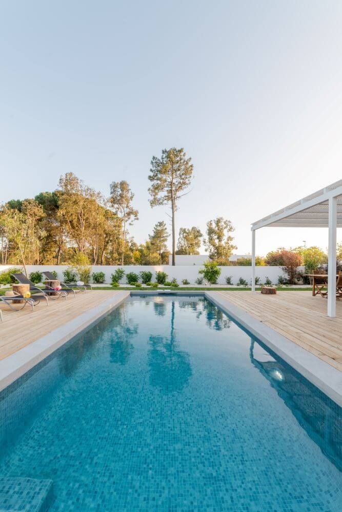 There is a large swimming pool in the backyard of a house.