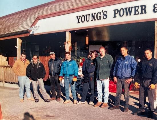 A group of men standing in front of a young 's power & equipment store