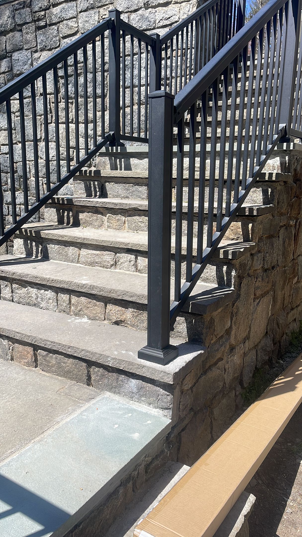 A set of stairs with a metal railing and a stone wall.