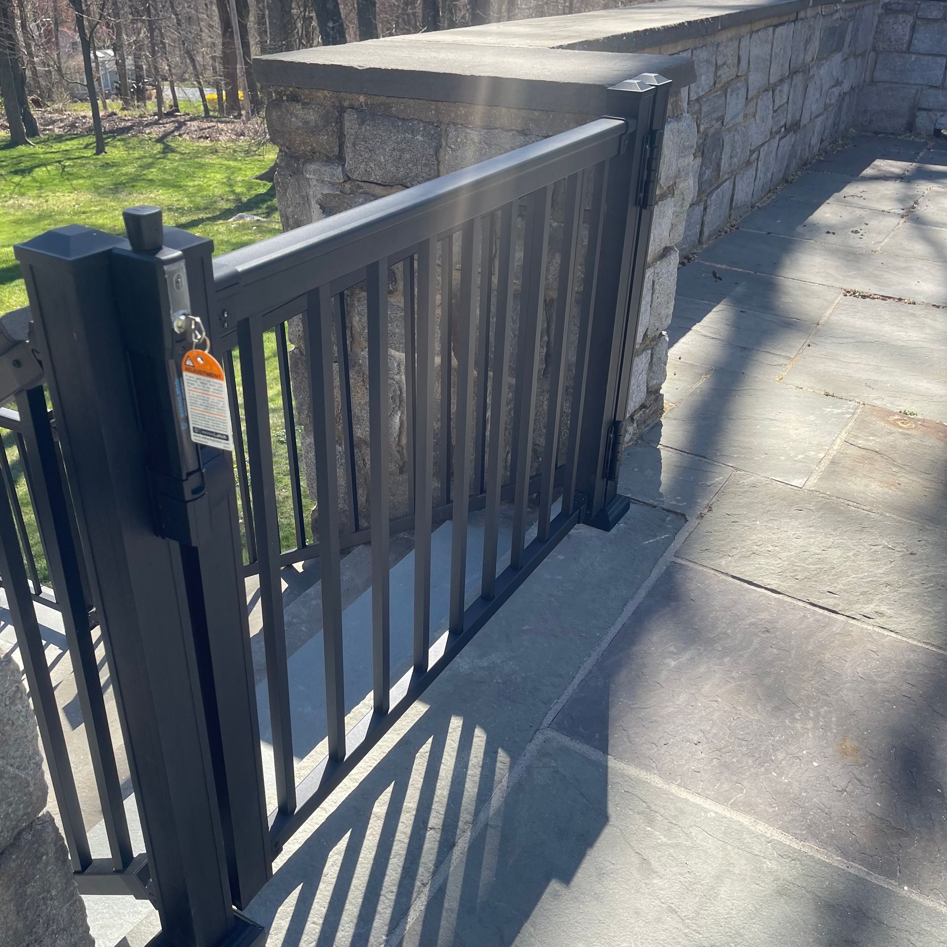 A black fence with a stone wall in the background