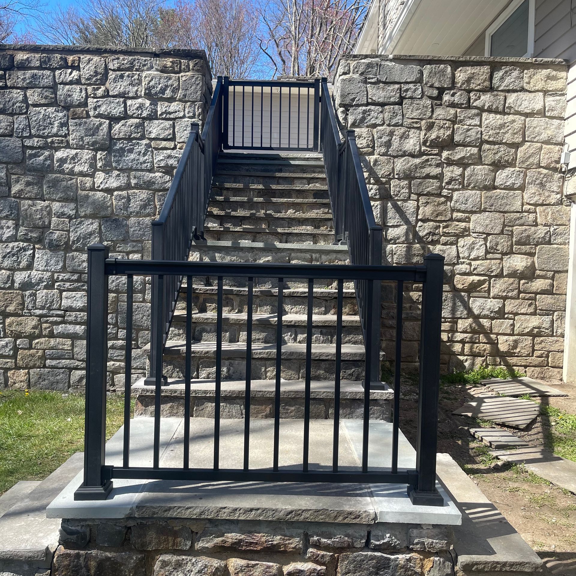Stairs leading up to a brick wall with a black railing