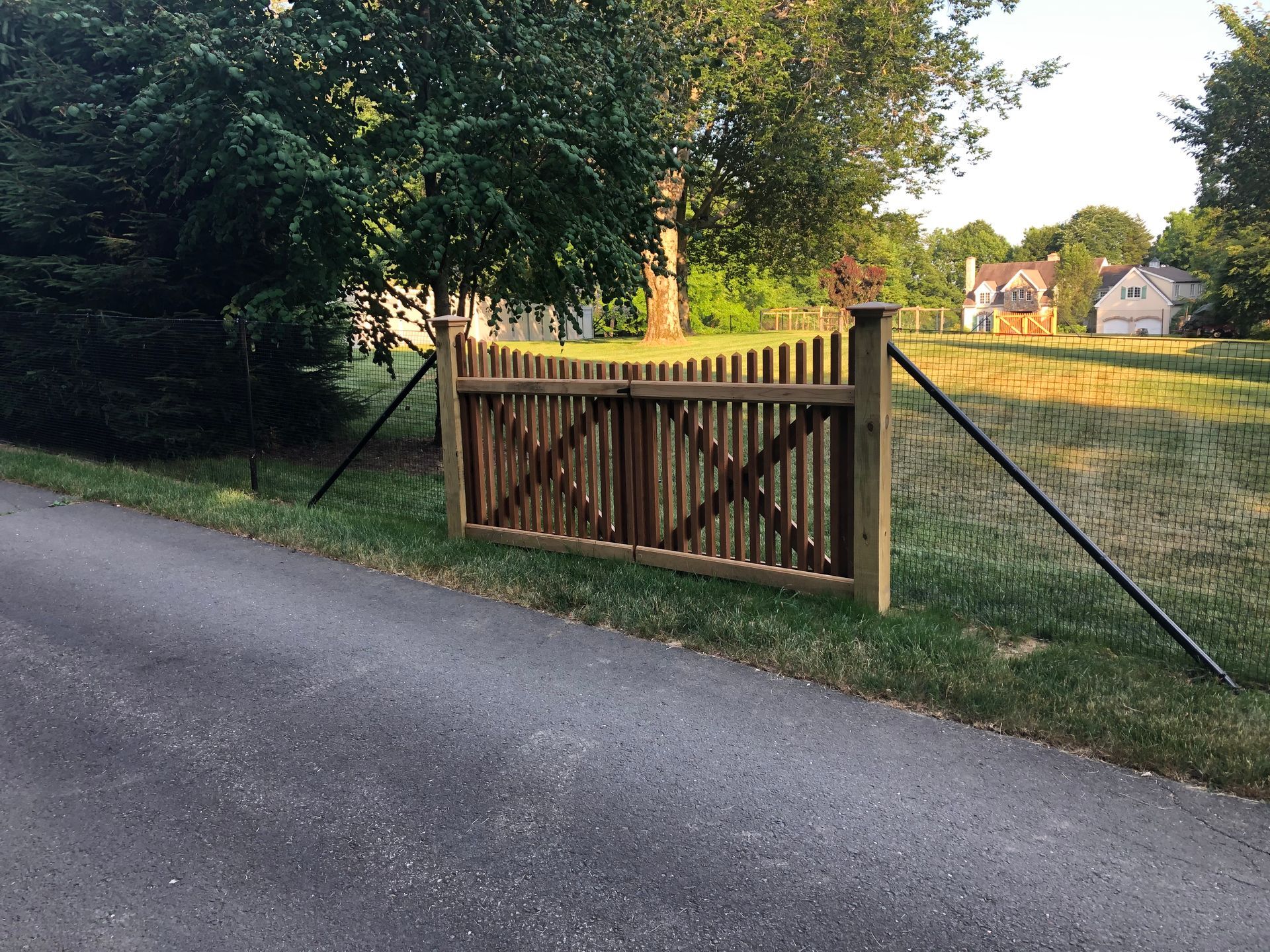 A wooden gate is sitting on the side of a road.