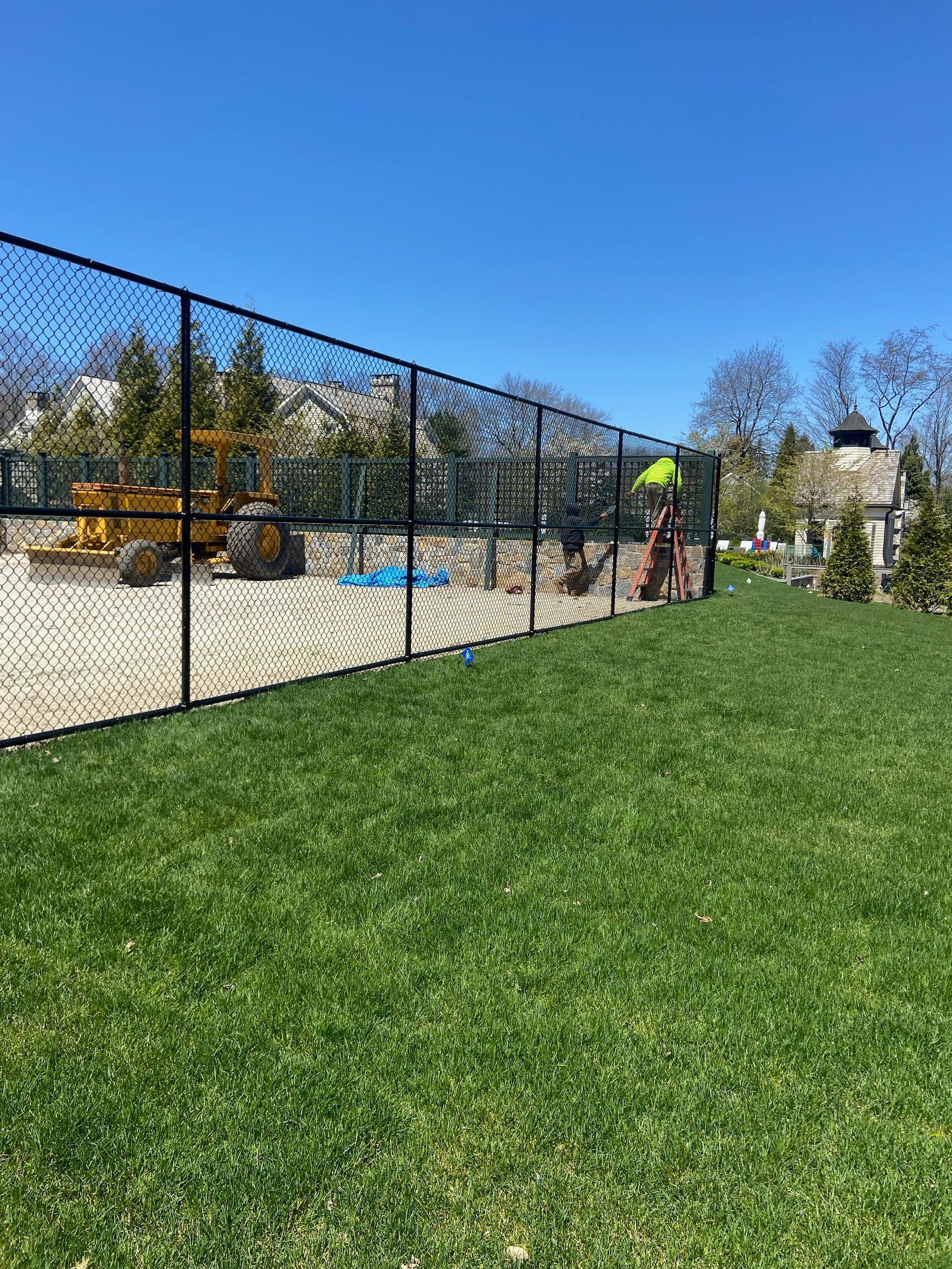 A fence surrounds a lush green yard with a playground in the background.