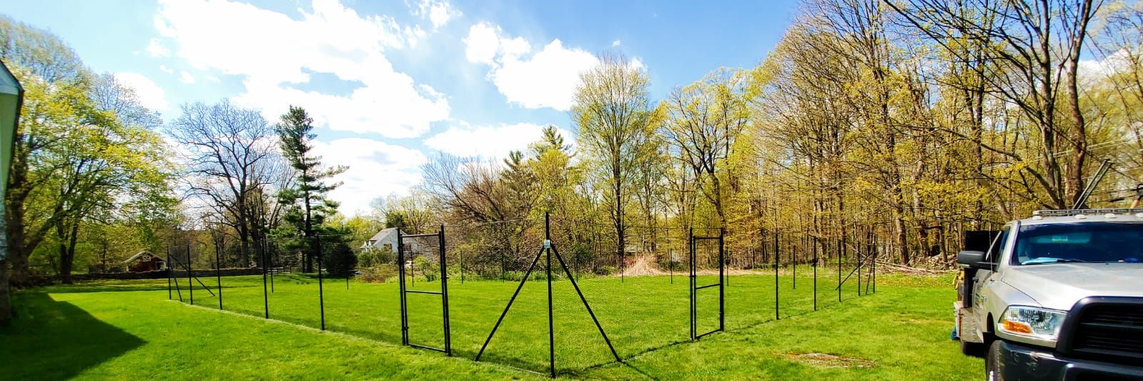 A truck is parked in a grassy field next to a fence.