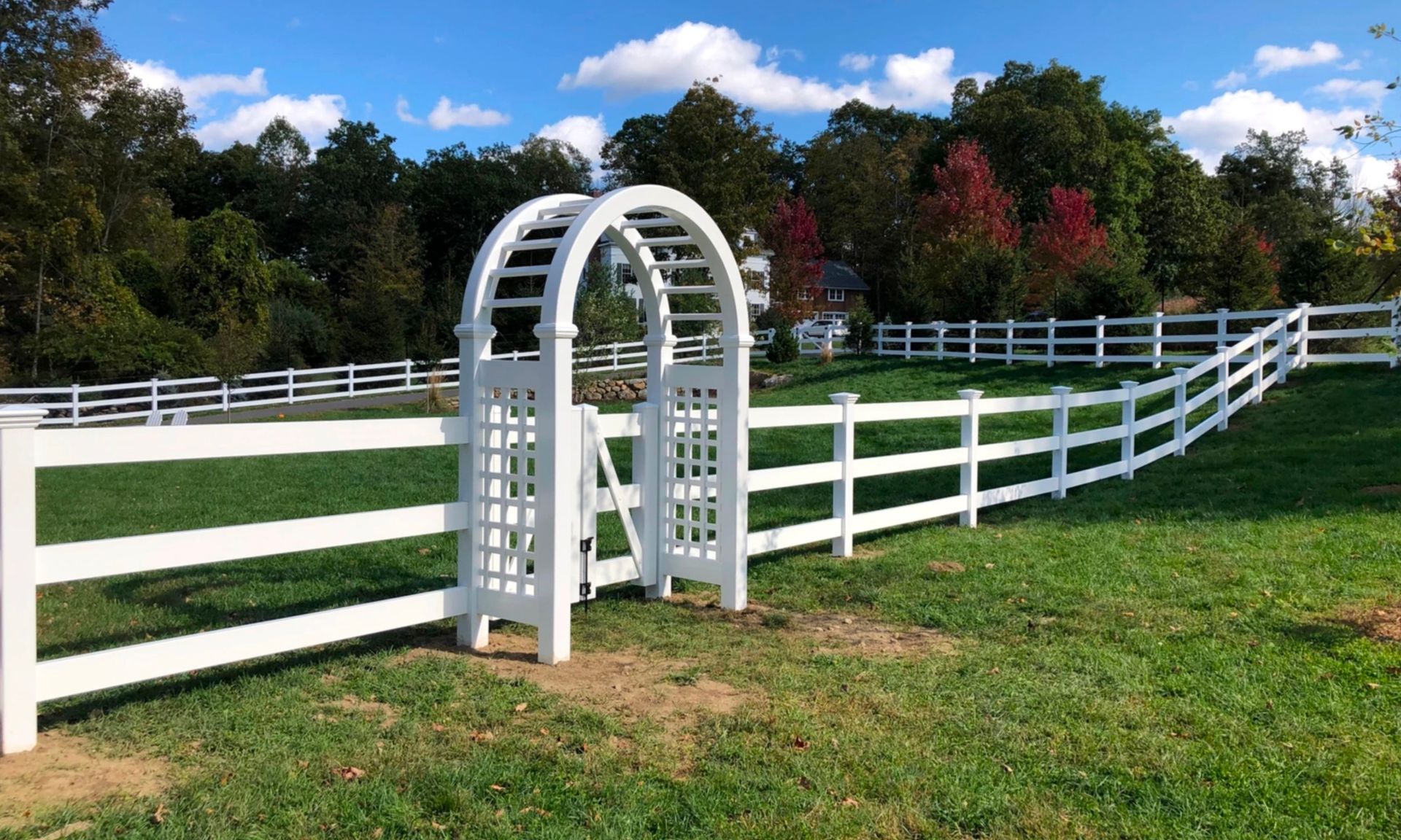 A white fence with a gate and an arbor in the middle of it